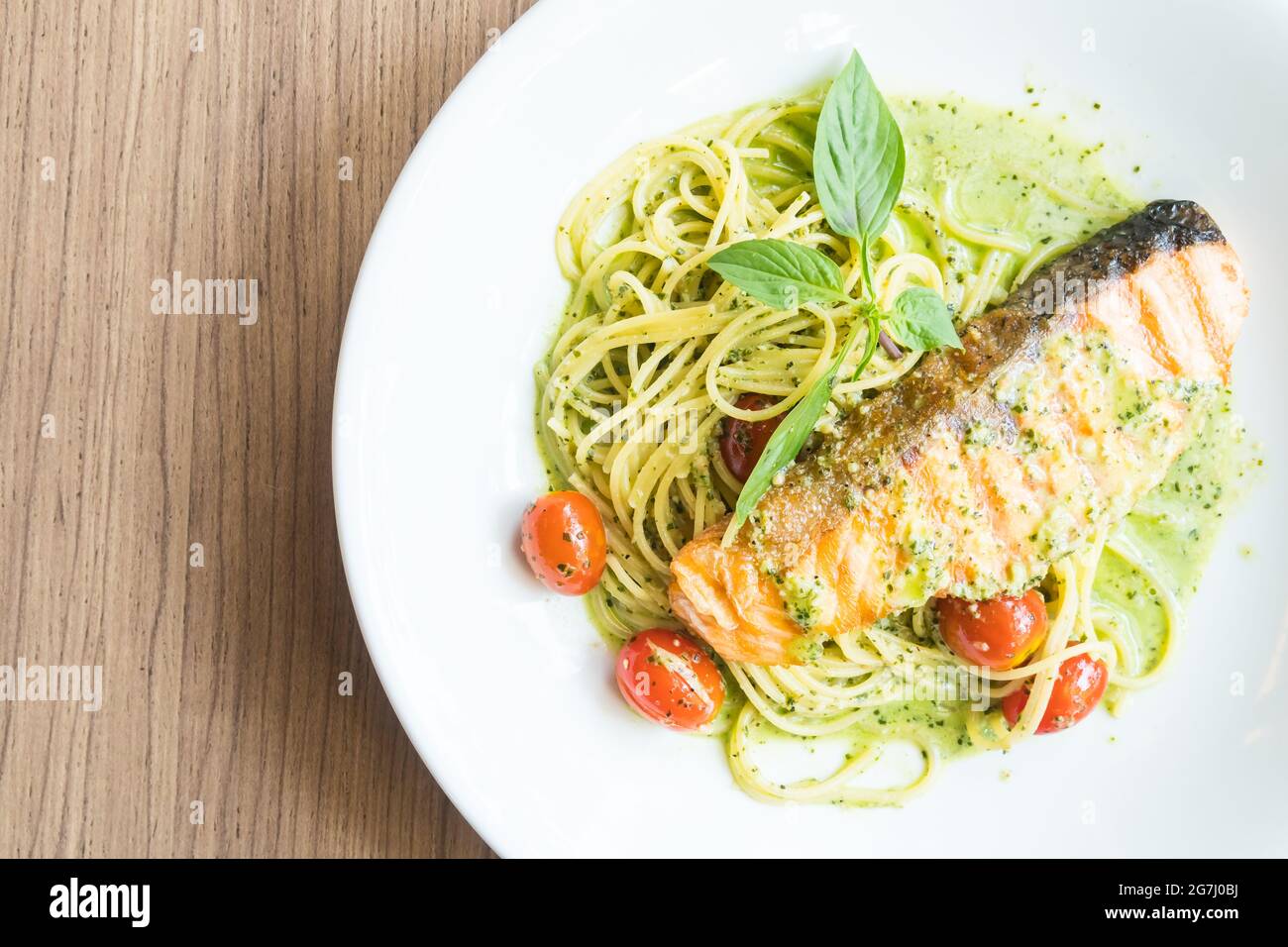 Spaghetti Pesto Lachs in weißem Teller auf Holztisch Stockfoto