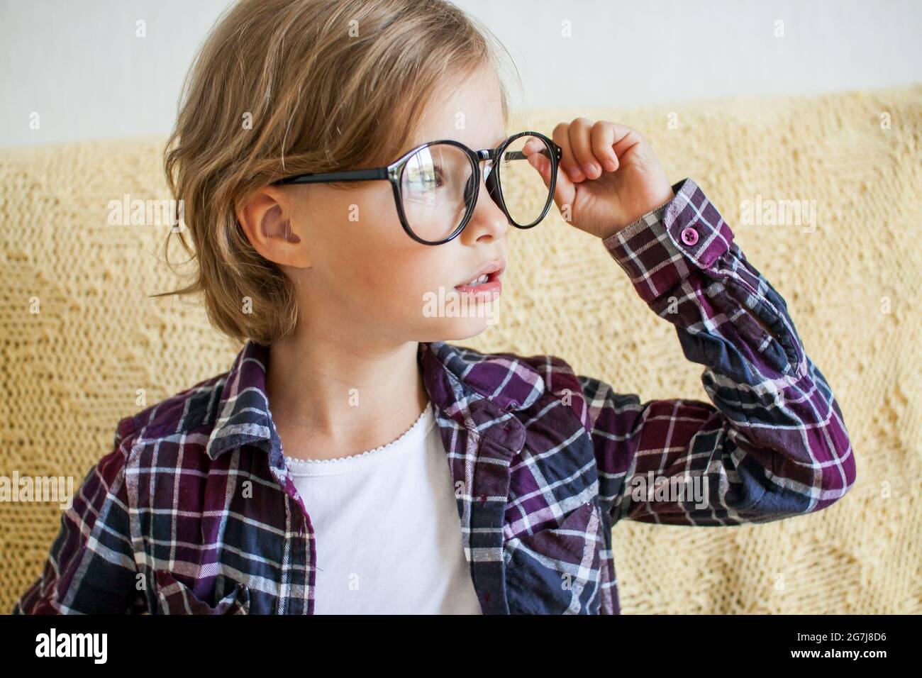 Fröhliches Mädchen in einem karierten Hemd und einer Brille. Online-Lernkonzept. Stockfoto