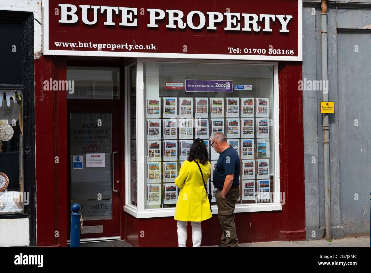Zwei Mitglieder, so f public, die Häuser zum Verkauf in Wind aus Immobilienagentur in Rothesay , Isle of Bute, Schottland, Großbritannien, betrachten Stockfoto