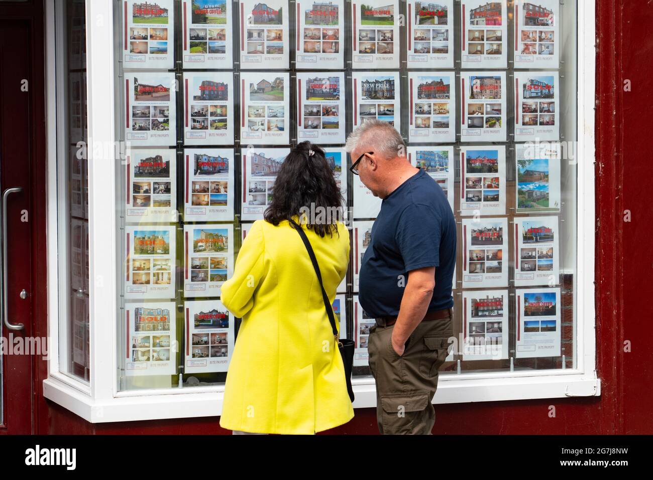 Zwei Mitglieder, so f public, die Häuser zum Verkauf in Wind aus Immobilienagentur in Rothesay , Isle of Bute, Schottland, Großbritannien, betrachten Stockfoto