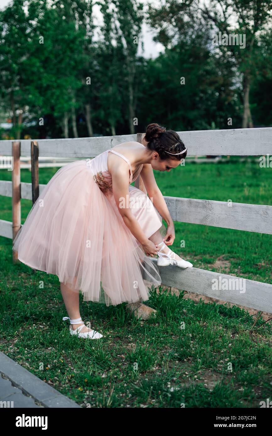 Lifestyle-Porträt einer Ballerina in einem rosa Kleid mit vollem Organza- Rock, das sich bis zum Bein beugt, um Bänder auf spitzenschuhen oder  Ballett zu binden Stockfotografie - Alamy