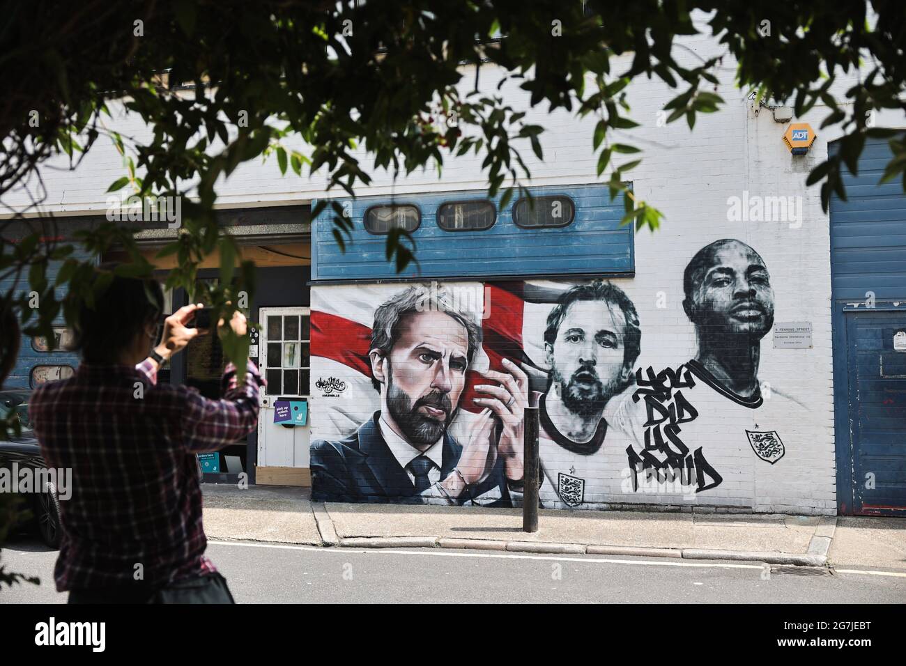 London, Großbritannien. Juli 2021. Ein Passant fotografiert das Wandbild des englischen Fußballmanagers Gareth Southgate und der Spieler Harry Kane und Raheem Sterling mit der Aufschrift „You did US stolze“ an einer Wand im Essig Yard in London. Das Wandbild wurde von MurWalls gemalt, nachdem die englische Fußballmannschaft es bis zum Finale der Euro 2020 erreicht hatte. Kredit: SOPA Images Limited/Alamy Live Nachrichten Stockfoto