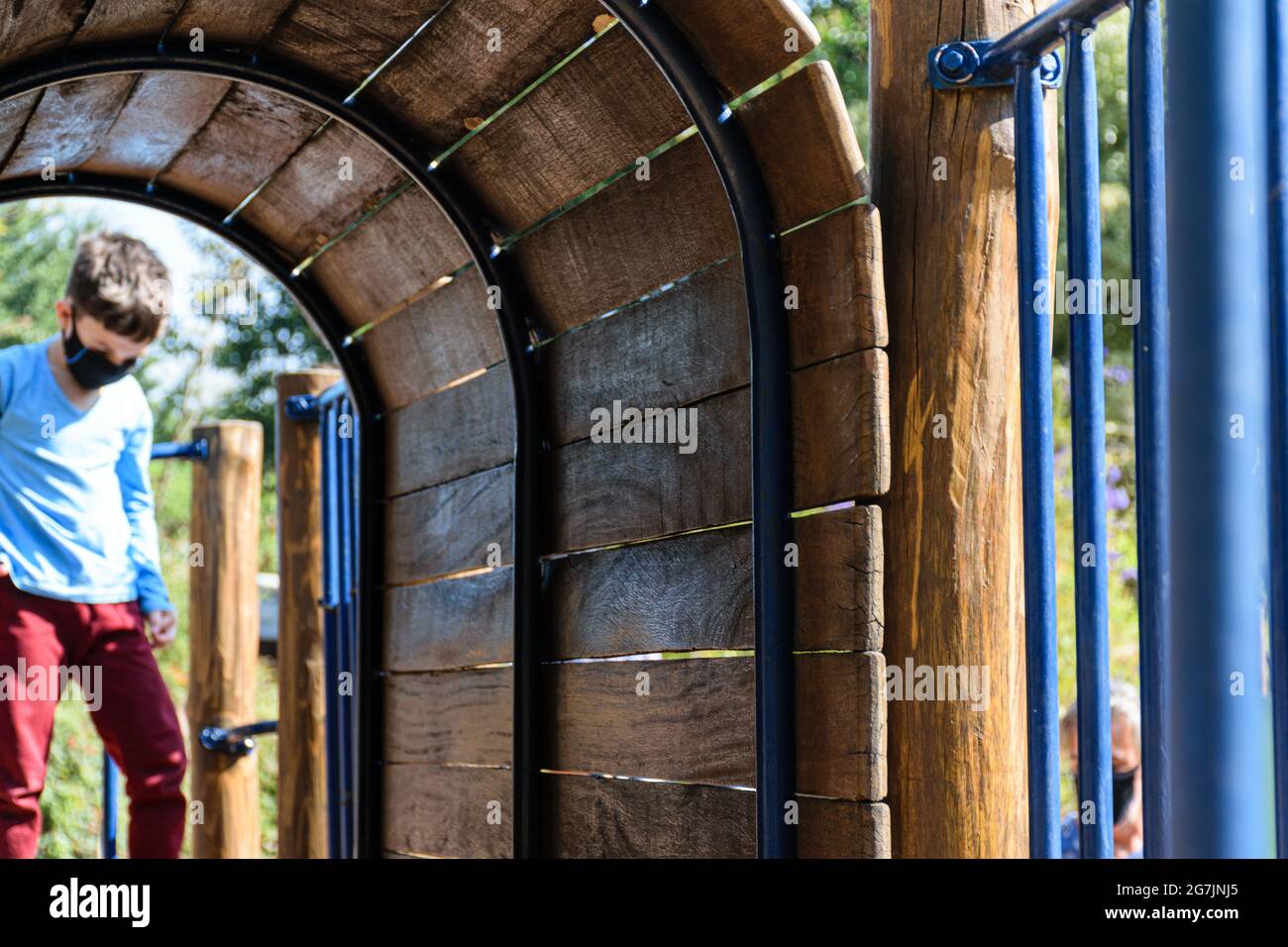 Mini-Holztunnel eines Spielzeugs im Park. Im unscharfen Hintergrund ein trauriges 8-jähriges Kind. Stockfoto