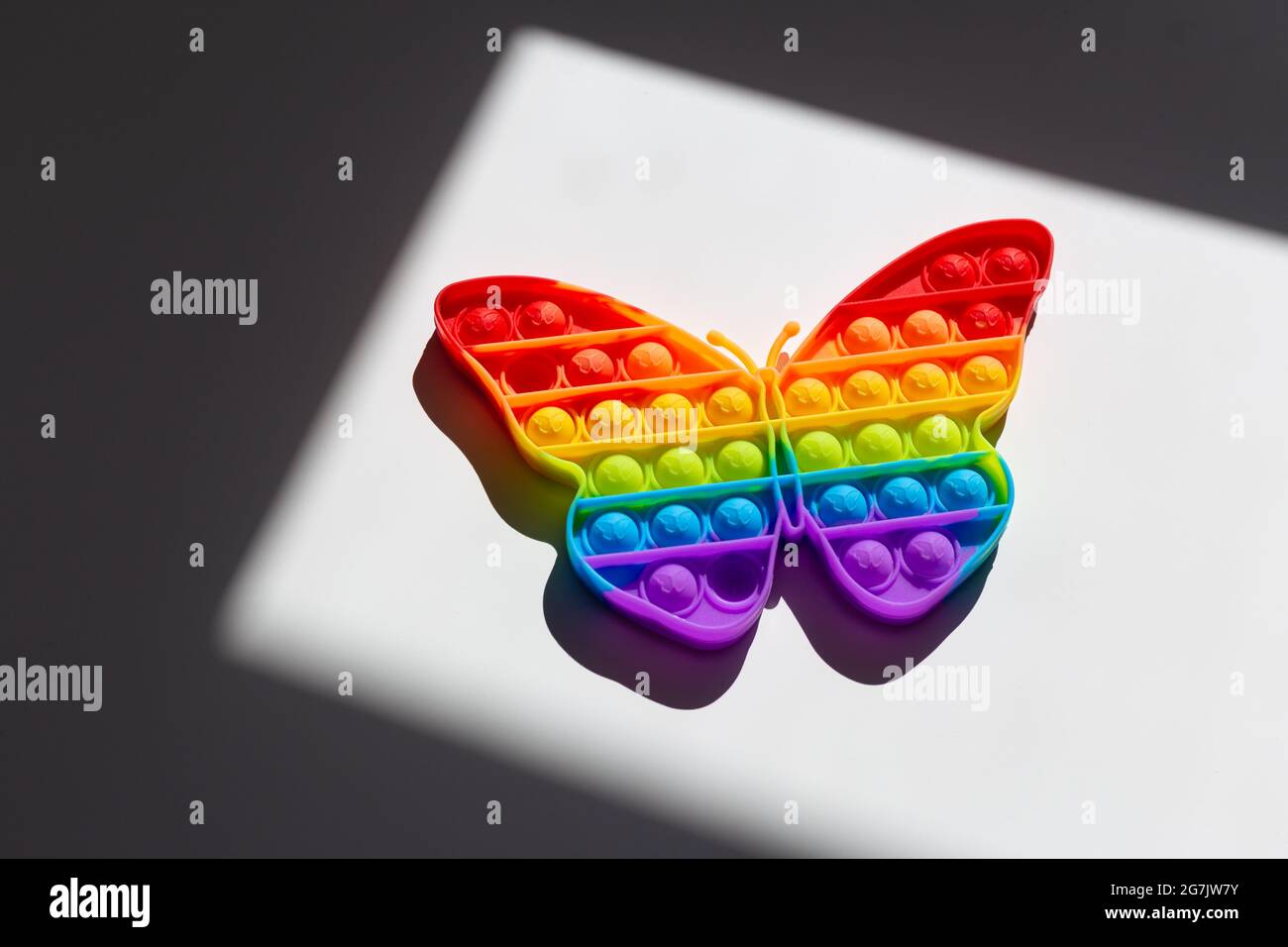 Regenbogenschmetterling. LGBT-Flaggensymbol-Konzept, Stolz, Liebe und Einheit. Kinderspielzeug Pop IT oder Simple Dimple in Form eines Regenbogenschmetterlings Stockfoto