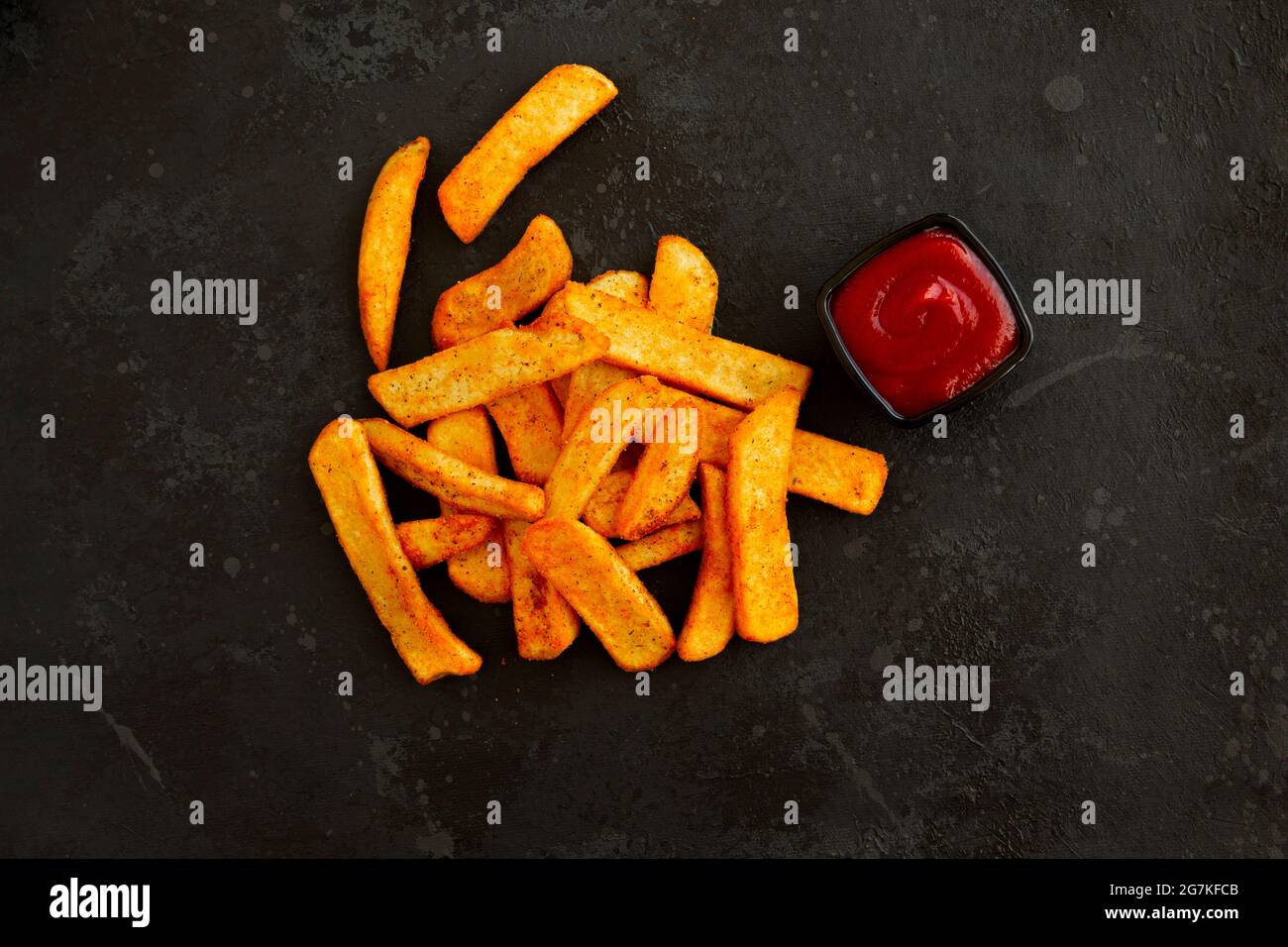 Gewürzte französische Kartoffeln und Ketchup auf dunklem Hintergrund Stockfoto