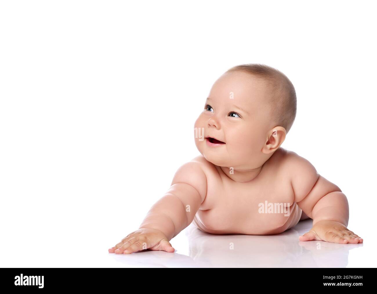 Glücklich lachend, kichernd Kleinkind Baby Mädchen Kind in Windel liegt auf ihrem Bauch mit ausgestrecktem Arm Stockfoto
