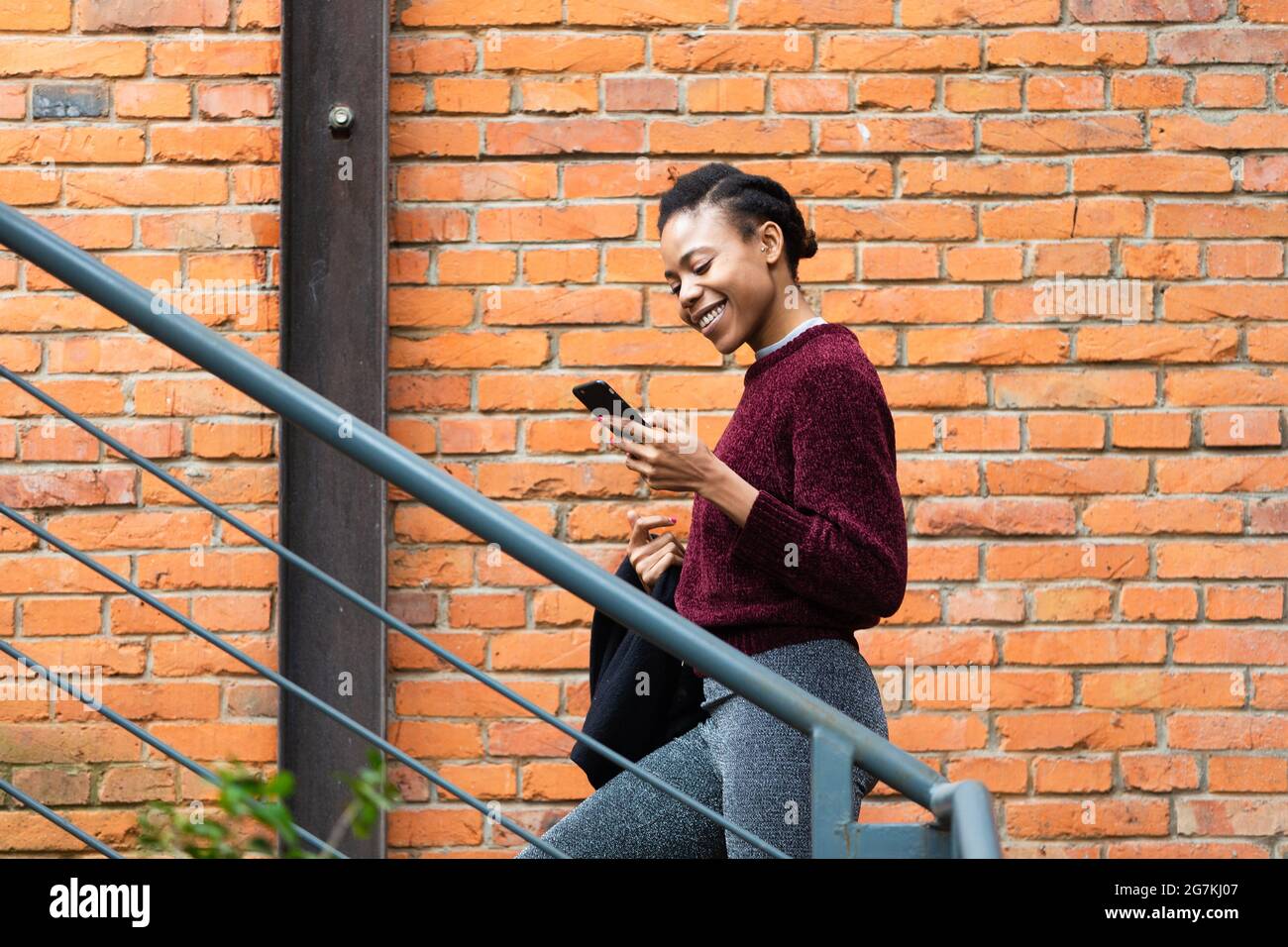 Schöne schöne afrikanische schwarze weibliche Geschäftsmann hält ein Handy zu Fuß auf der Treppe und glücklich lesen Nachrichten Stockfoto