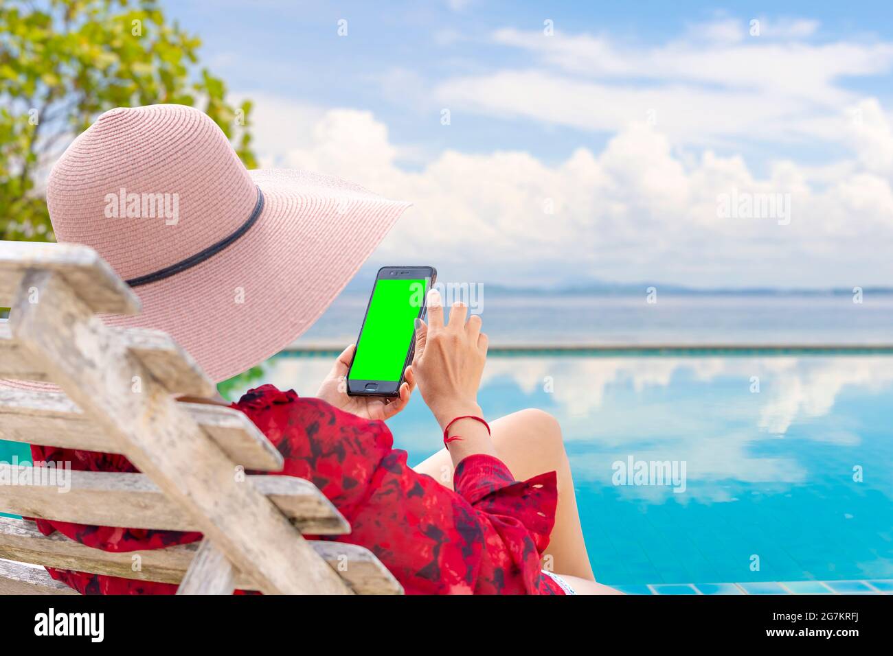 Frau mit Smartphone am Pool. Ihre Hände berühren den grünen Telefonbildschirm. Für die Schöpfer zusätzliche Bilder zu setzen. Stockfoto