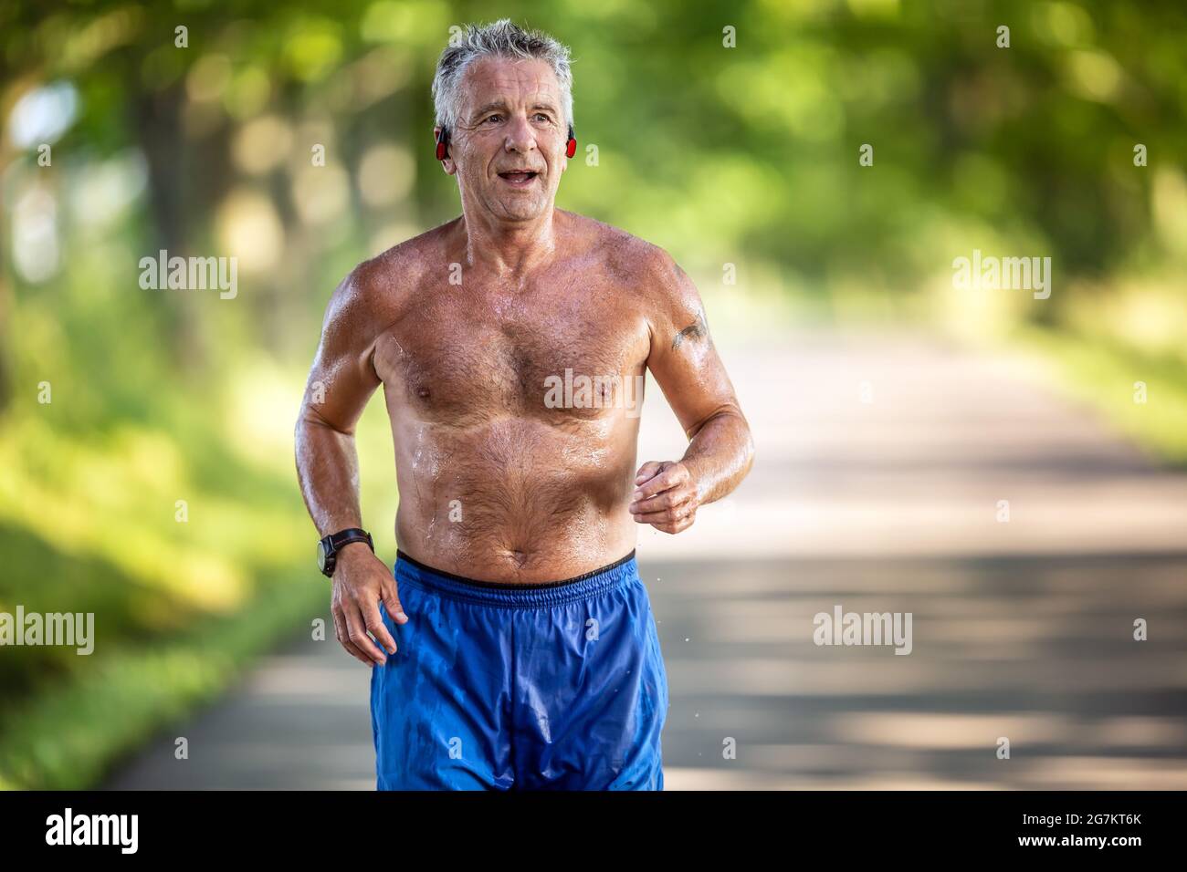 Ein sehr feingetauhter Mann in den 70ern läuft nur in seinen Shorts im Freien in der Natur. Stockfoto