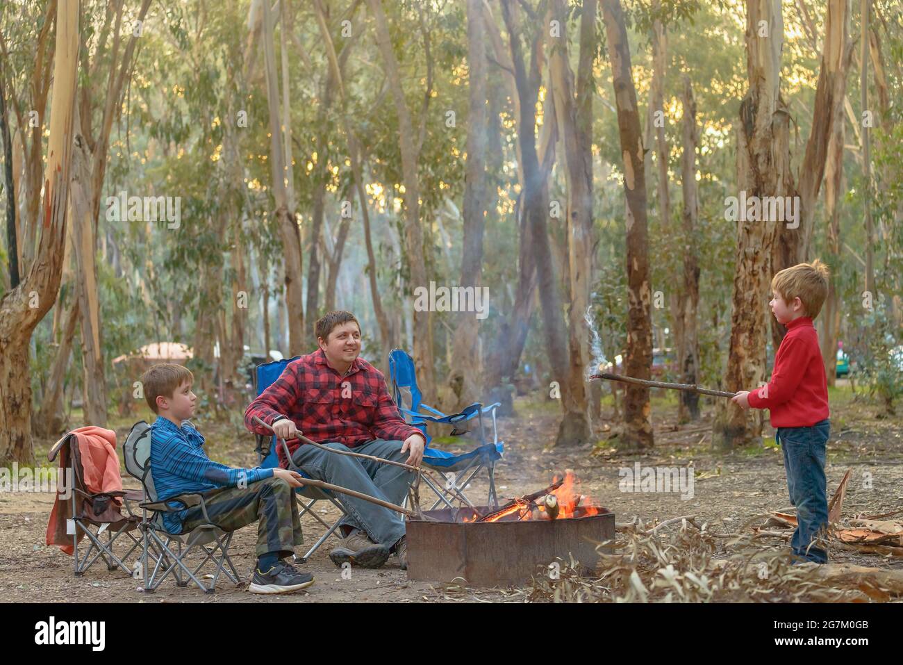 Kinder mit Vater brennendes Feuer auf Kuitpo Wald Camping Boden Schulferien Stockfoto