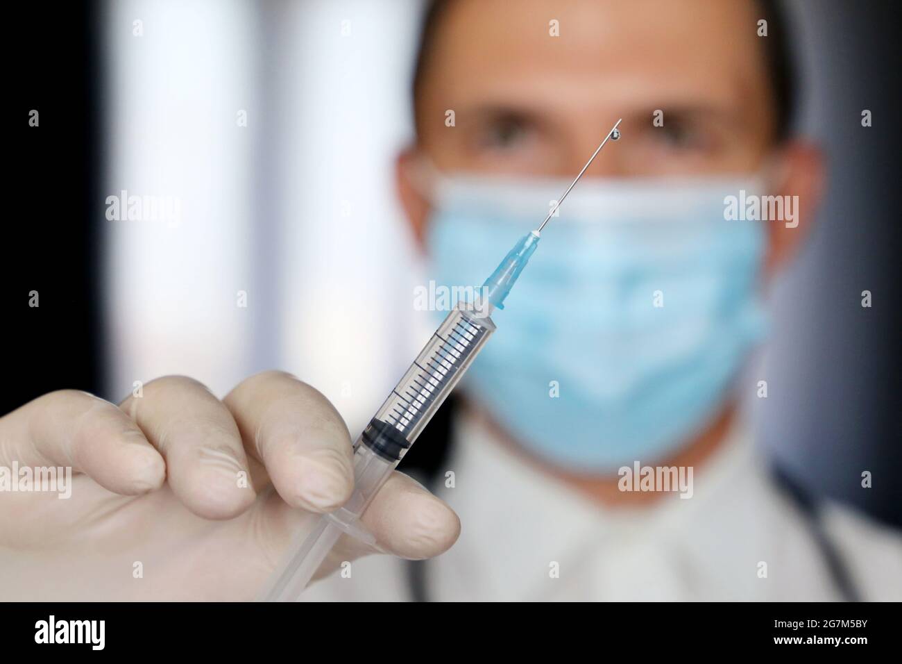 Arzt mit Spritze in der Hand, Mann in medizinischer Maske Vorbereitung auf die Injektion. Konzept der Impfung während einer Covid-19-Pandemie Stockfoto