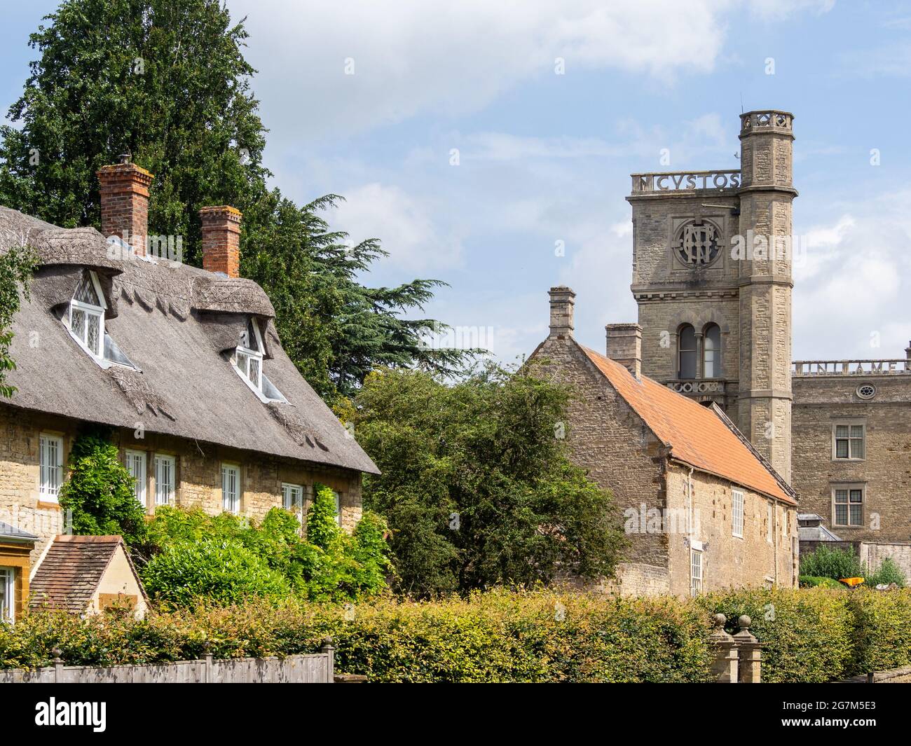 Malerische Szene im Gutsdorf Castle Ashby, Northamptonshire, Großbritannien; Reethaus und viktorianischer Wasserturm. Stockfoto