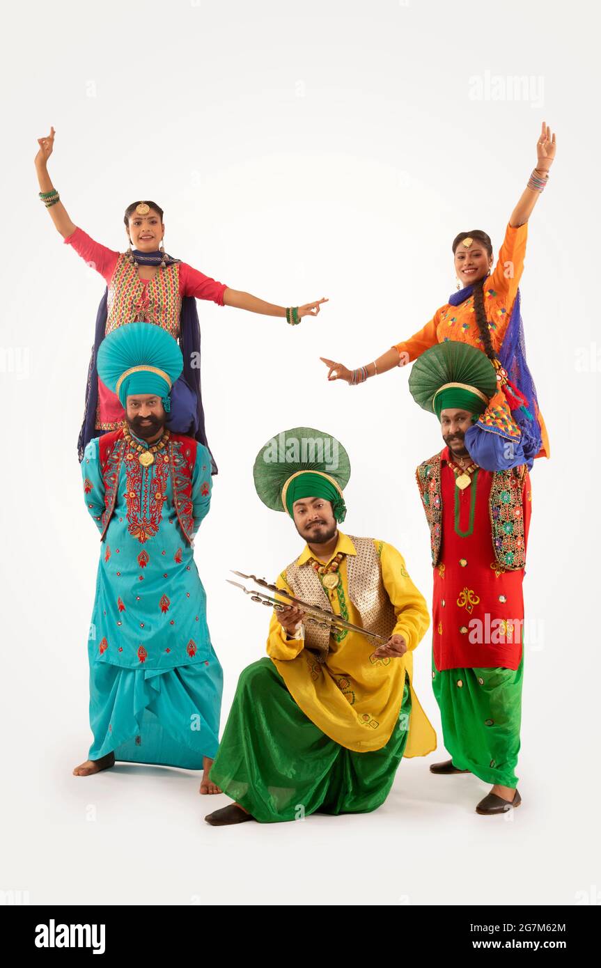 Zwei Bhangra-Tänzerinnen mit Giddha-Tänzern auf dem Rücken und ein dritter mit Chimta. Stockfoto