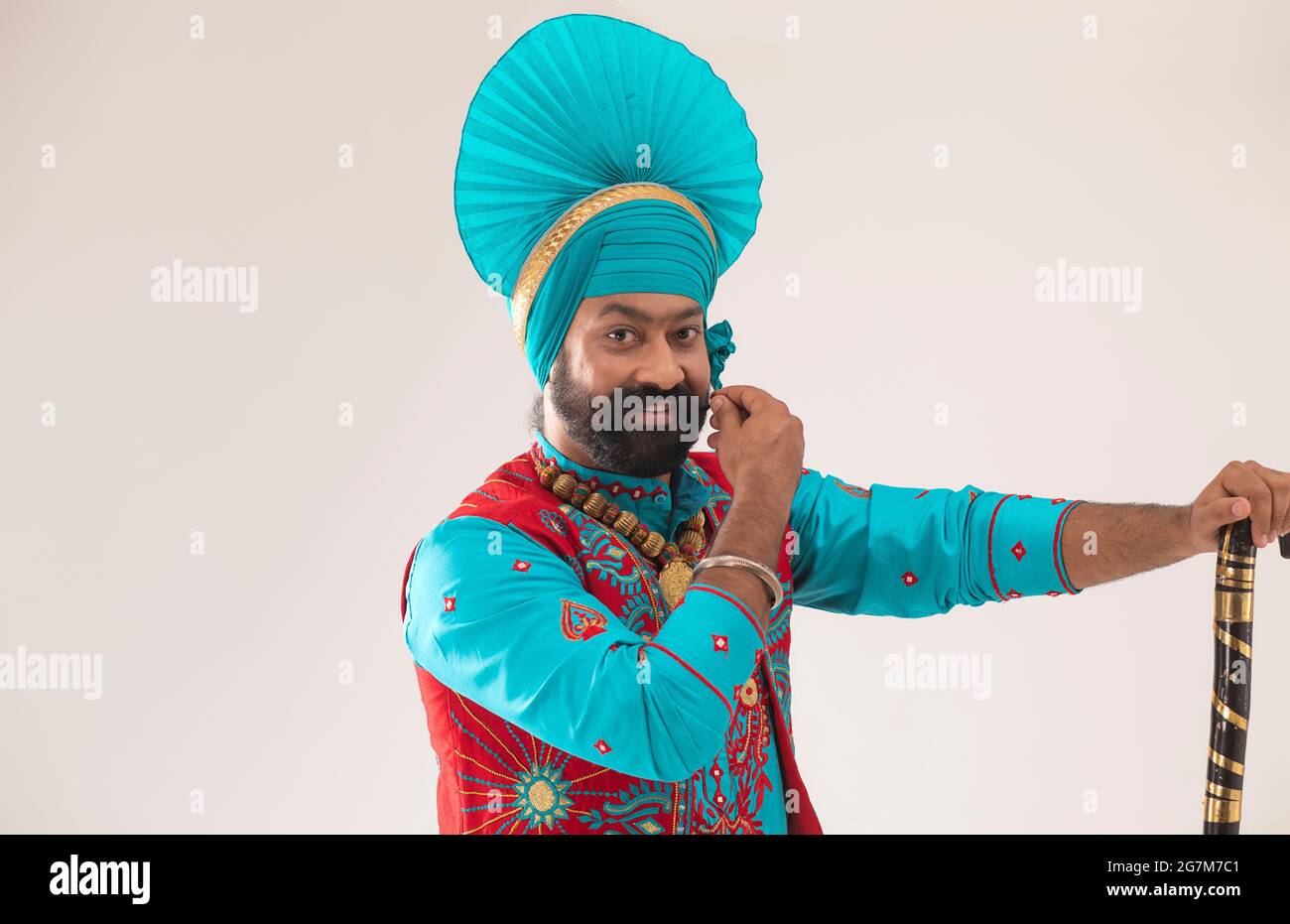 Ein Bhangra-Tänzer streichelte seinen Bart mit einer Khunda in der Hand. Stockfoto