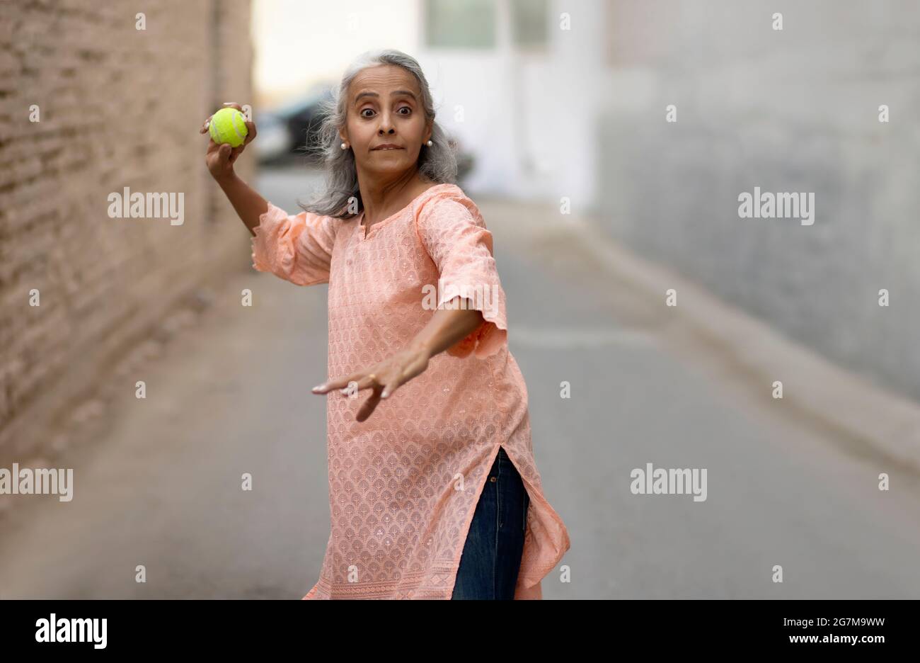 Eine alte Frau spielt Cricket Bowling. Stockfoto