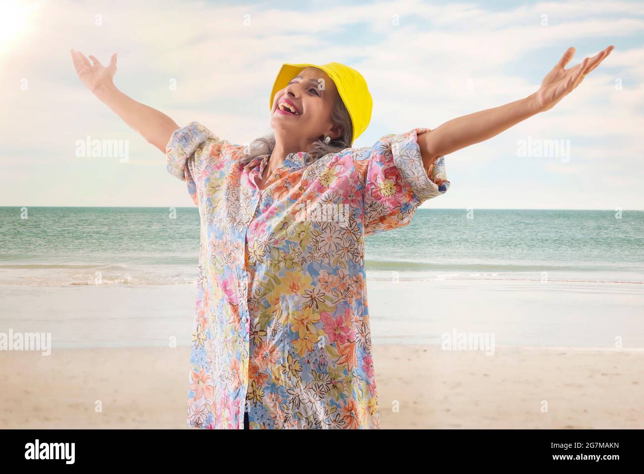 Eine alte Frau, die sich am Strand sonnt Stockfoto