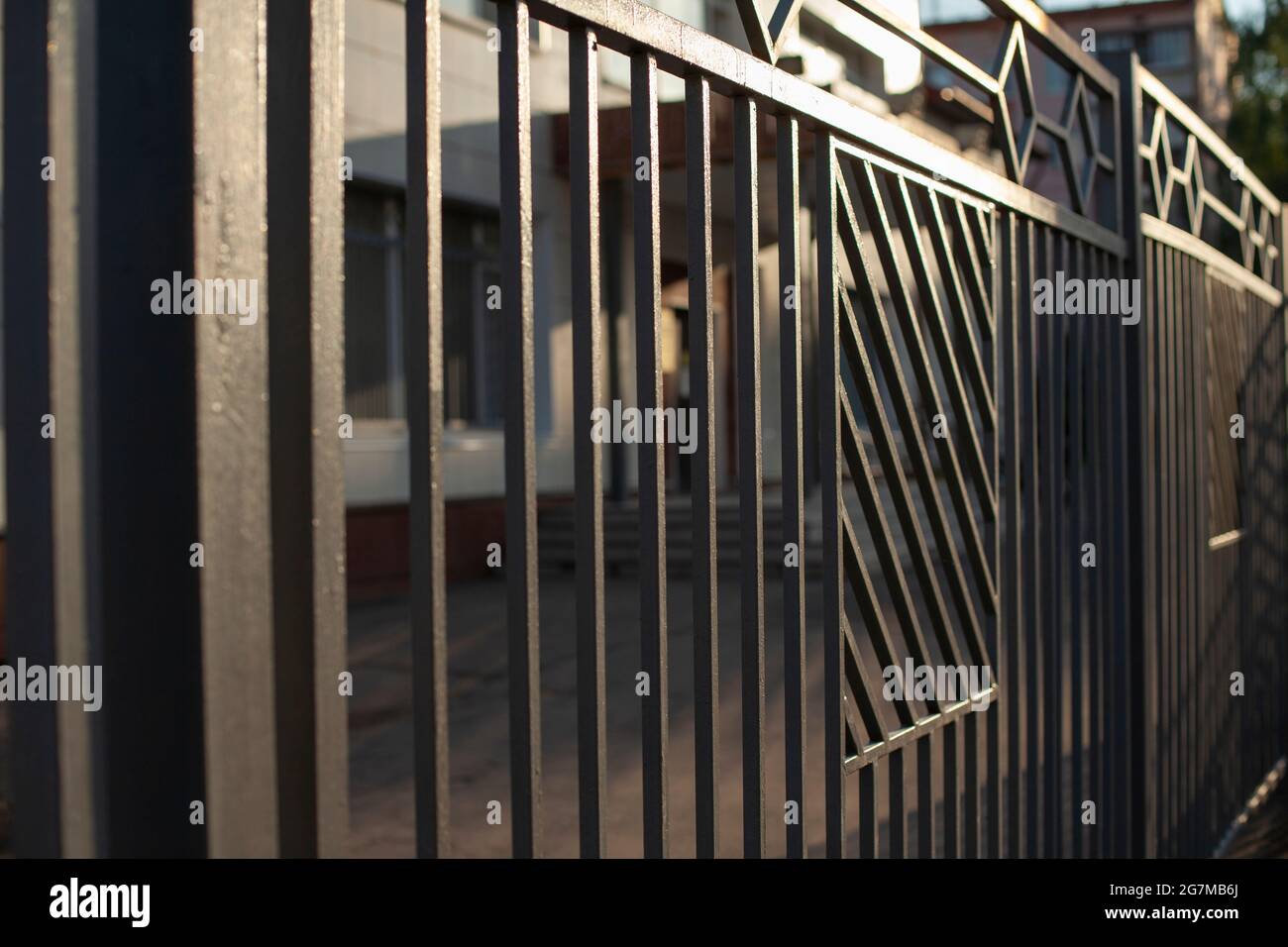 Der Zaun auf der Straße. Der alte Zaun in der Stadt. Eine Hecke um Privatland. Stockfoto