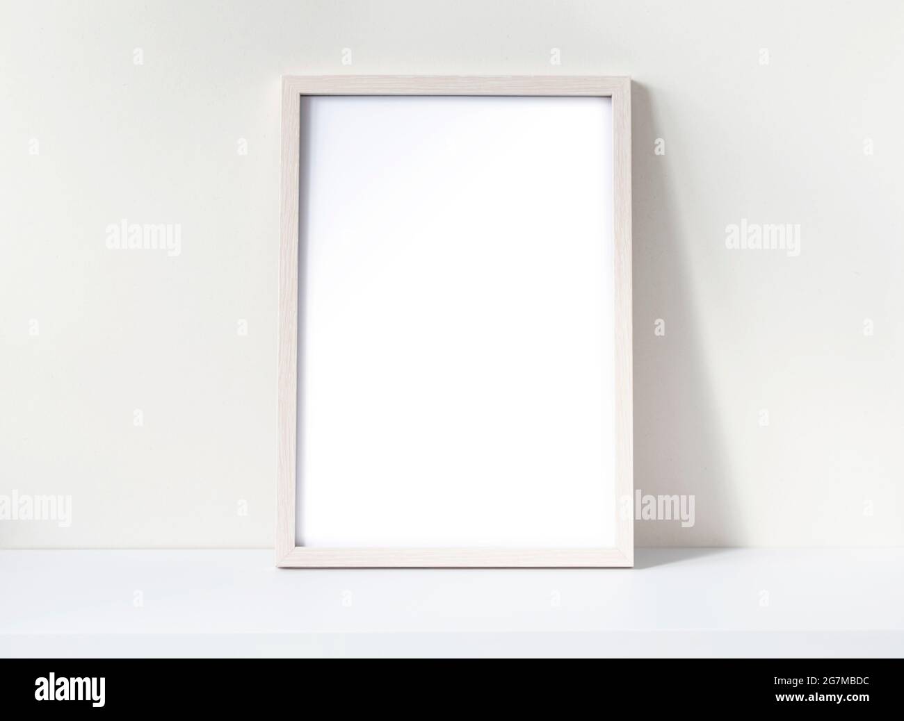 Fotorahmen-Modell mit weißem leeren Blatt auf einem weißen Schreibtisch. Nachbau aus Kiefernholz. Platz für Text. Stockfoto