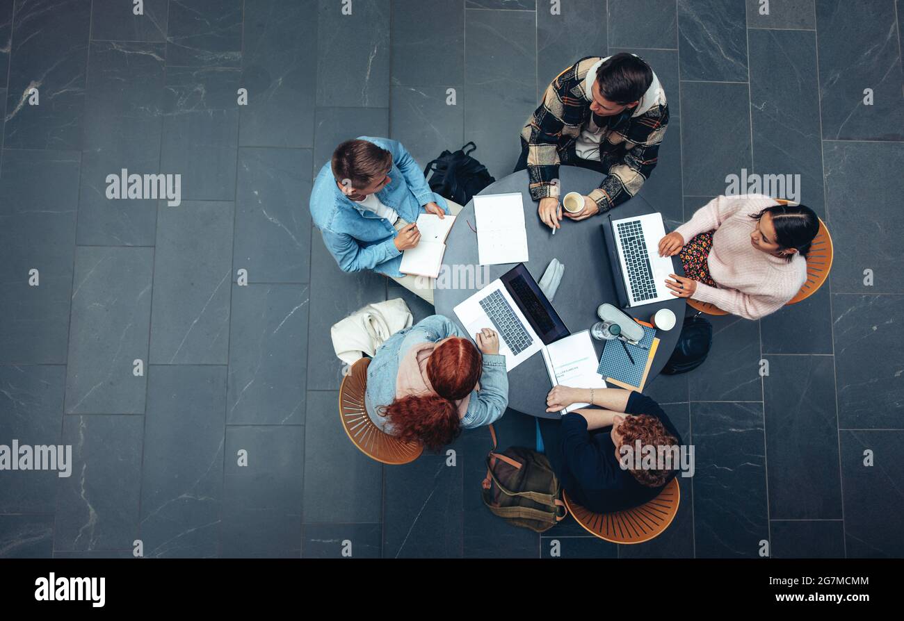 Draufsicht einer Gruppe von Schülern, die zusammen am Tisch sitzen. Studierende, die ein Gruppenstudium absolvieren. Stockfoto