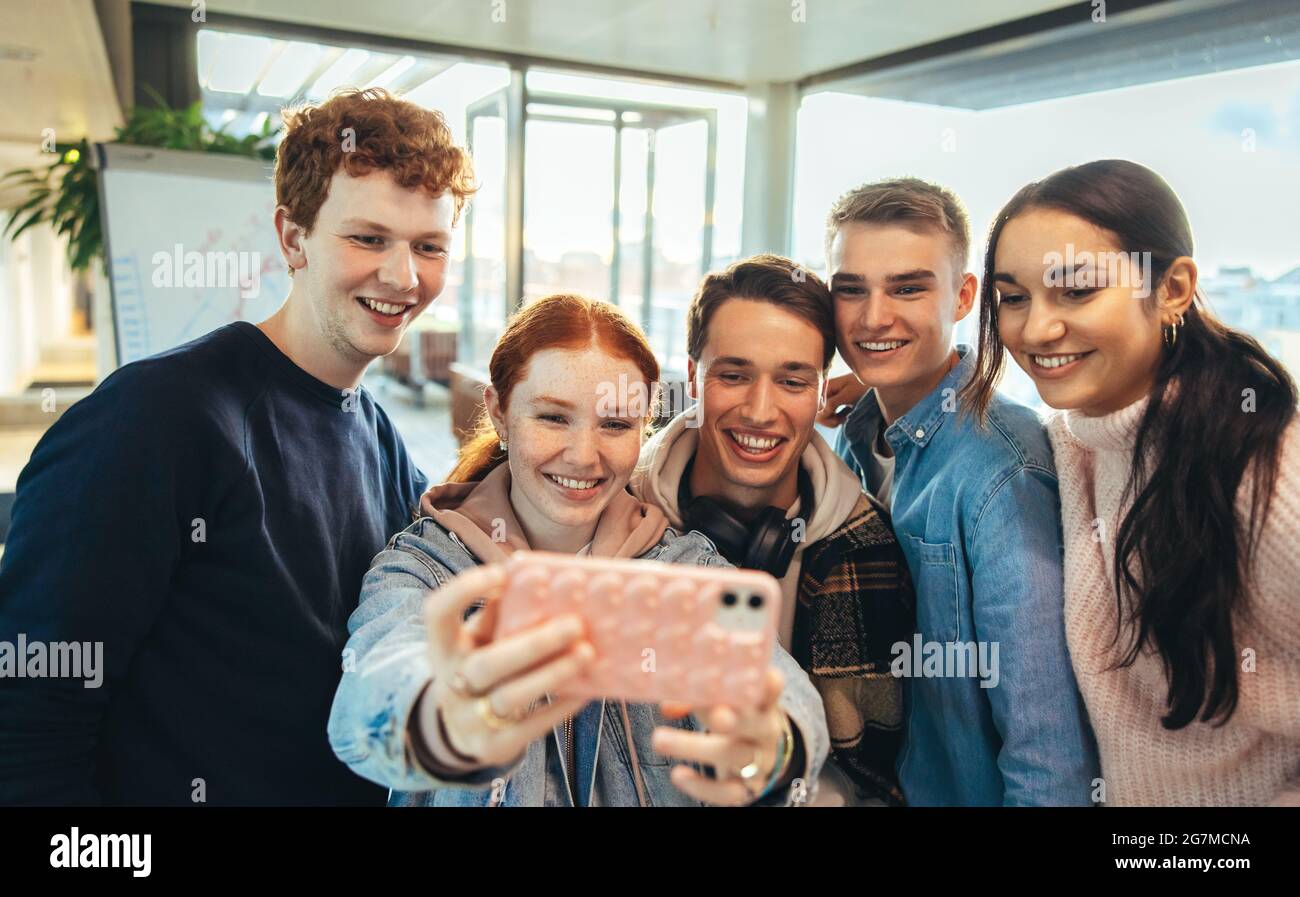 Glückliche Freunde, die Selfie in der Universität machen. Mädchen nimmt Selfie mit ihren Freunden in der Universität. Stockfoto