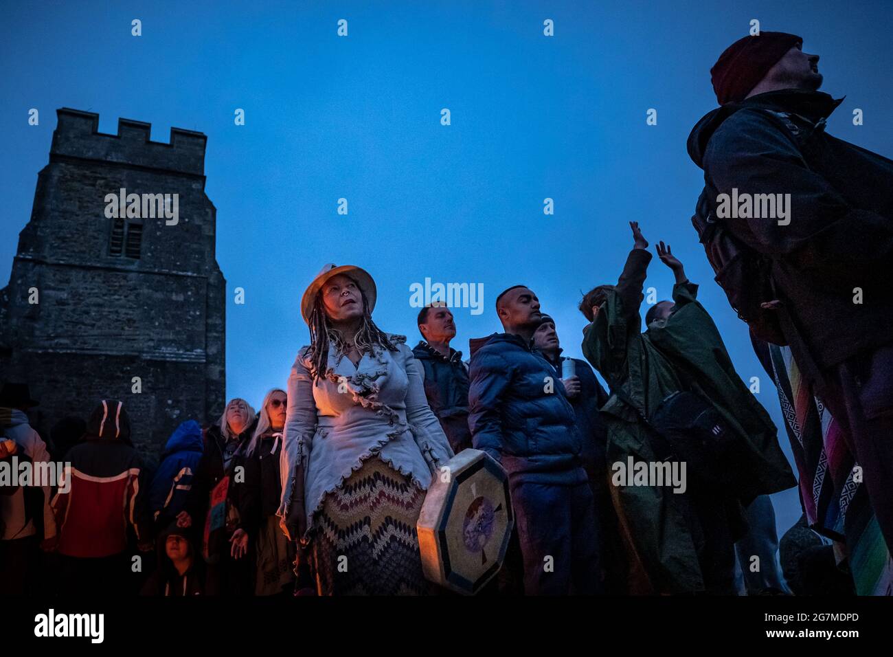 Sommersonnenwende am Glastonbury Tor mit Feiernden, die sich versammeln, um die Ankunft des Sommers und den längsten Tag des Jahres zu begrüßen. Somerset, Großbritannien Stockfoto