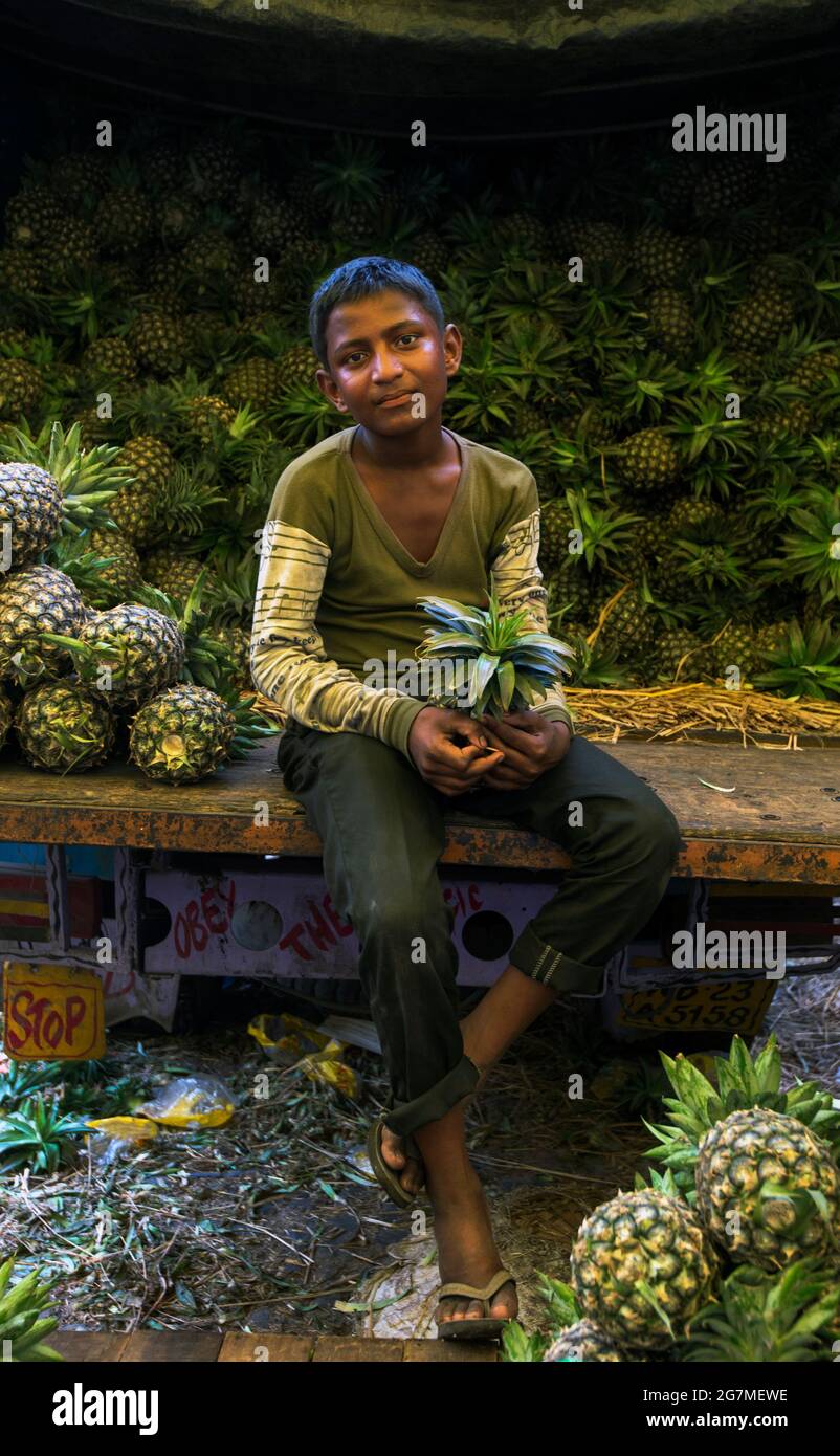 Junge, die Ananas verkauft. Der Fruchtbasar des muslimischen Viertels rund um die Nakhoda-Moschee ist ein Labyrinth aus Mini-Basaren und verwinkelten Gassen. Stockfoto