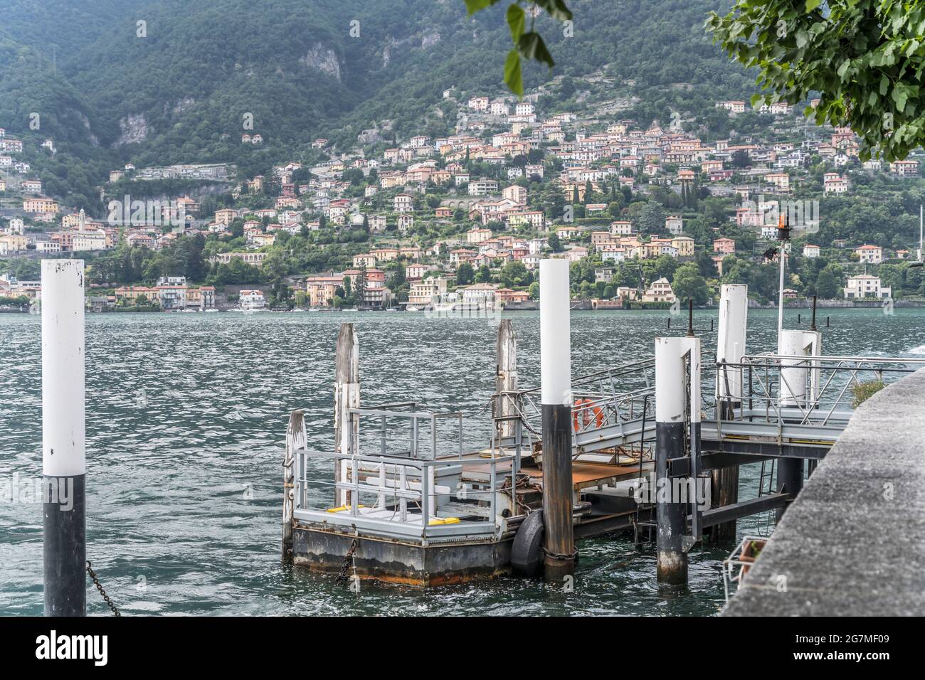 Touristische Schiffslandung am Seeufer, aufgenommen im Sommer in Torno mit Moltrasio Dorf im Hintergrund, Como, Italien Stockfoto