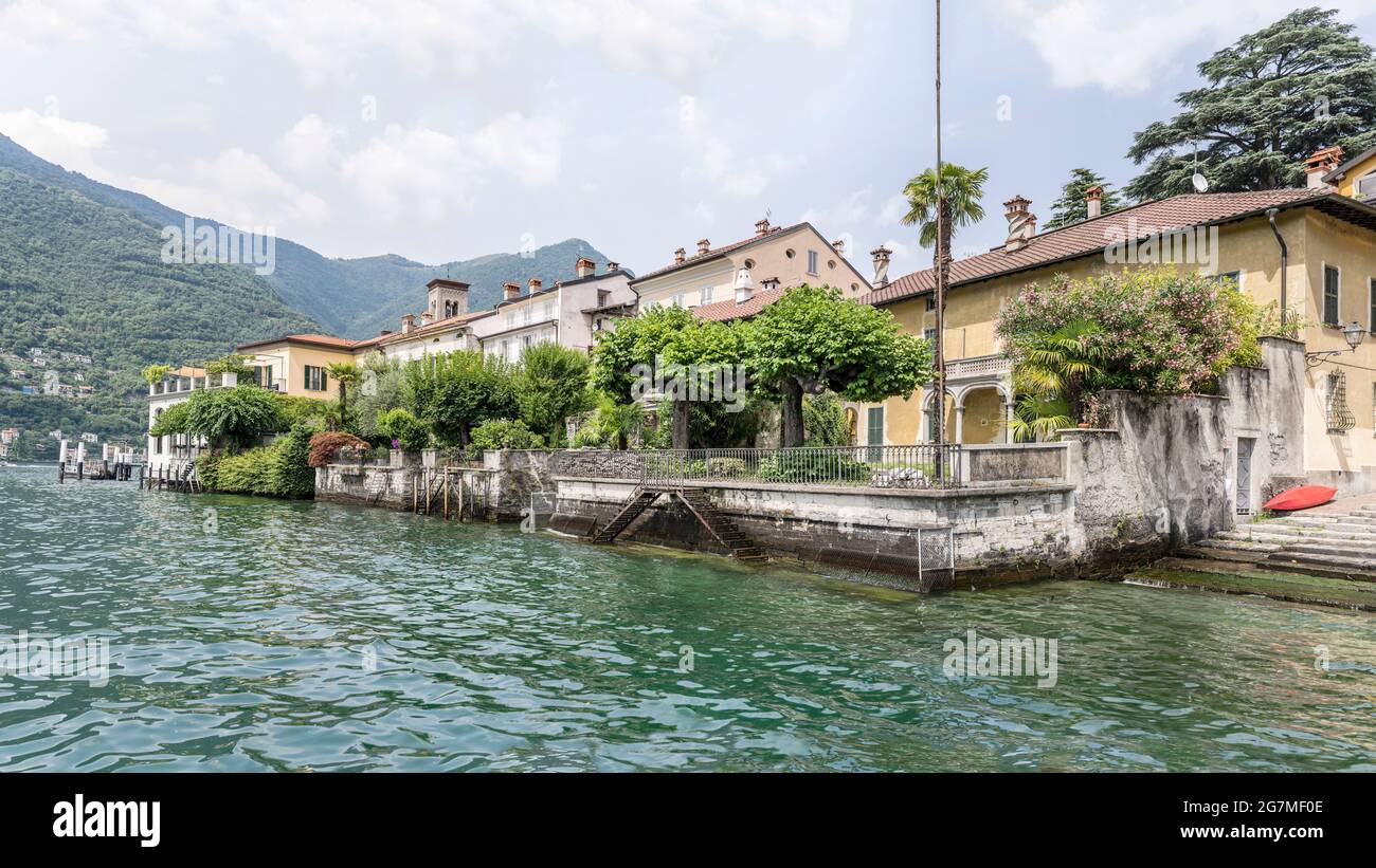 Stadtbild mit malerischen Häusern auf dem Wasser im Dorf am Seeufer im Sommer, aufgenommen in Torno, Como, Italien Stockfoto