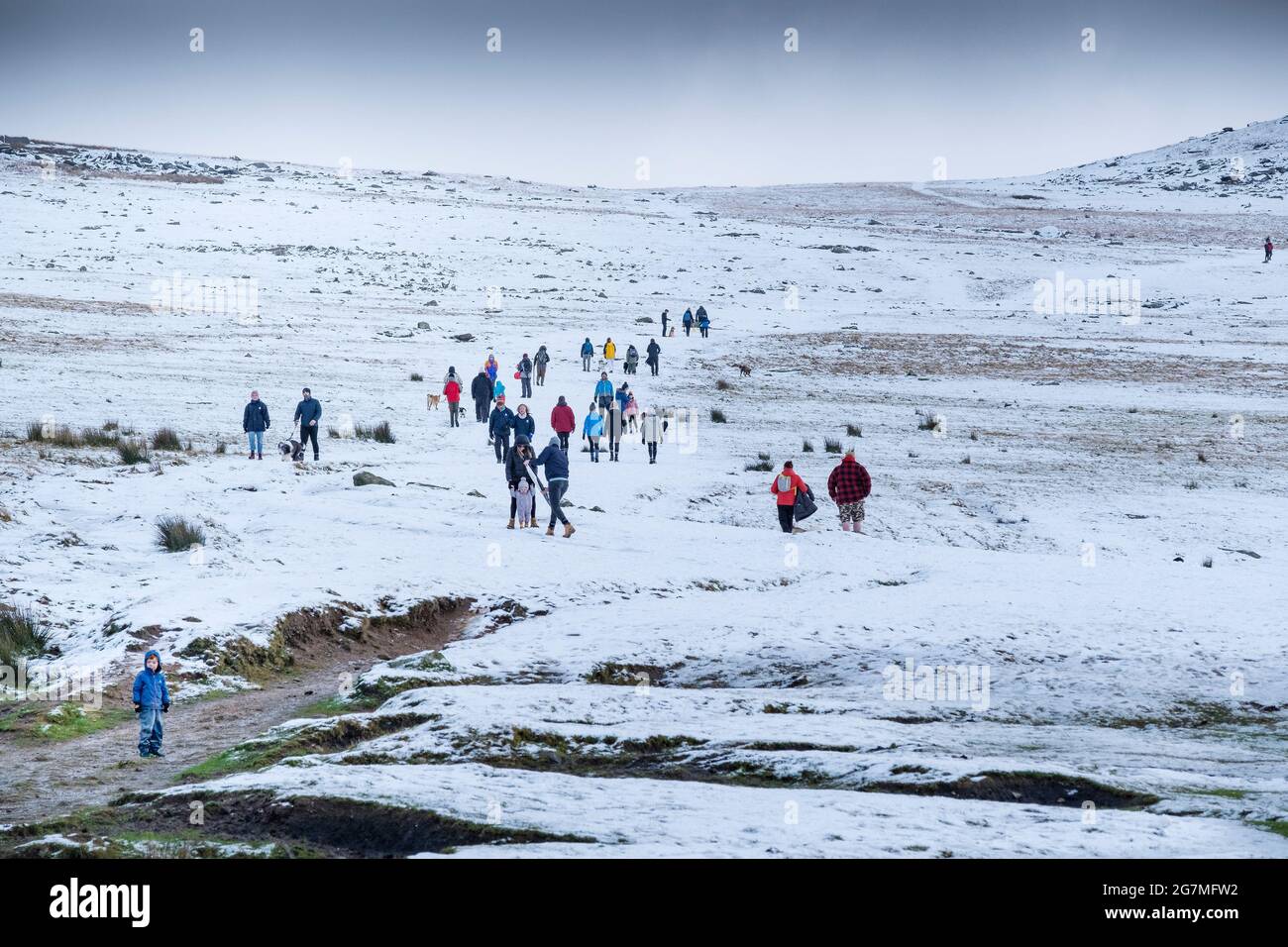 Menschen genießen einen Spaziergang im Schnee auf Rough Tor auf Bodmin Moor in Cornwall. Stockfoto