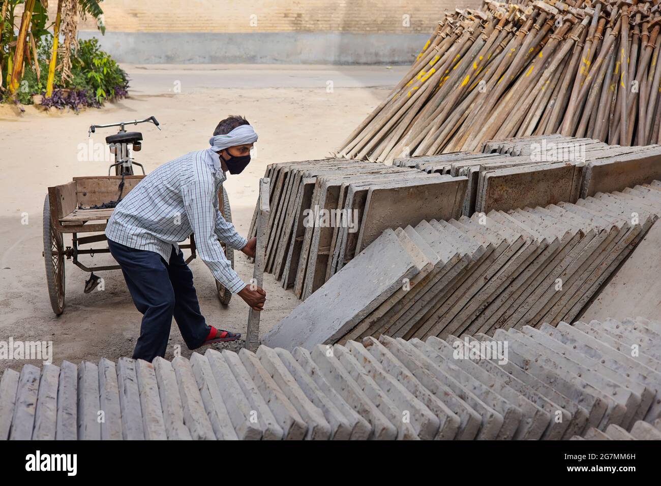 EIN ARBEITER, DER EINEN GROSSEN BLOCK ZIEGEL ZUSAMMENHÄLT Stockfoto