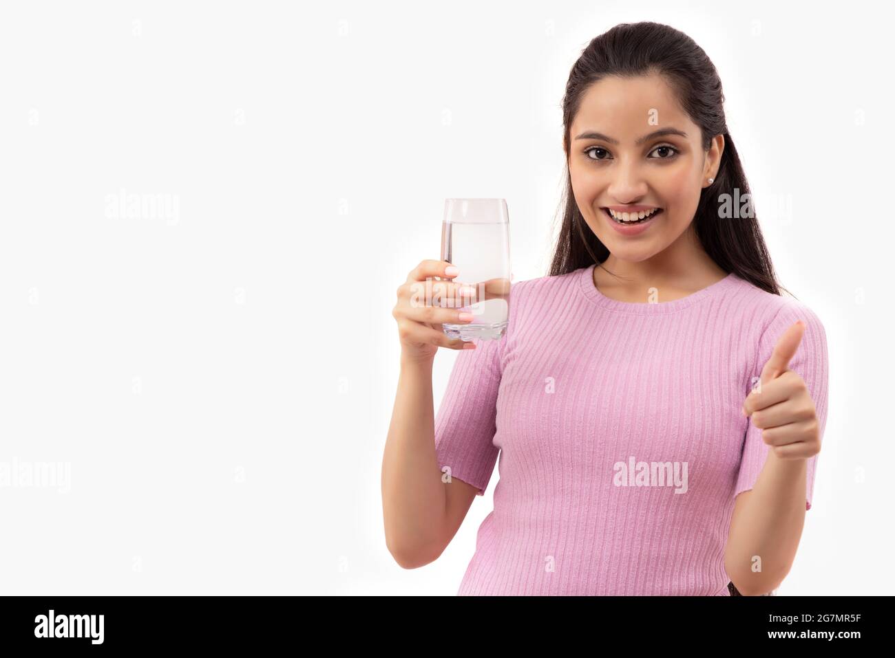 PORTRÄT EINES TEENAGERS, DAS MIT EINEM GLAS WASSER IN DER HAND STEHT Stockfoto