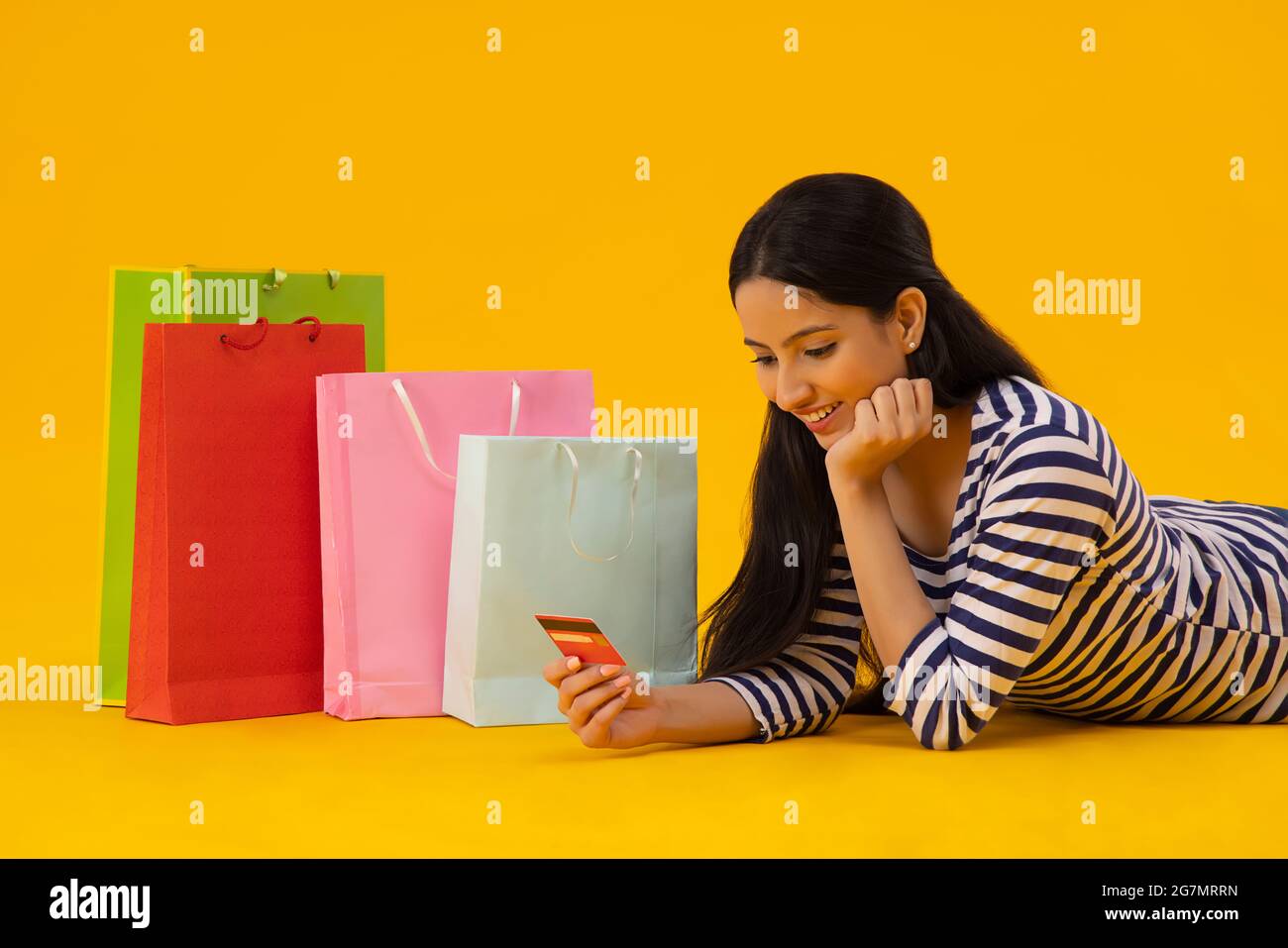Eine junge Frau mit Kreditkarte und Tragetaschen an ihrer Seite. Stockfoto