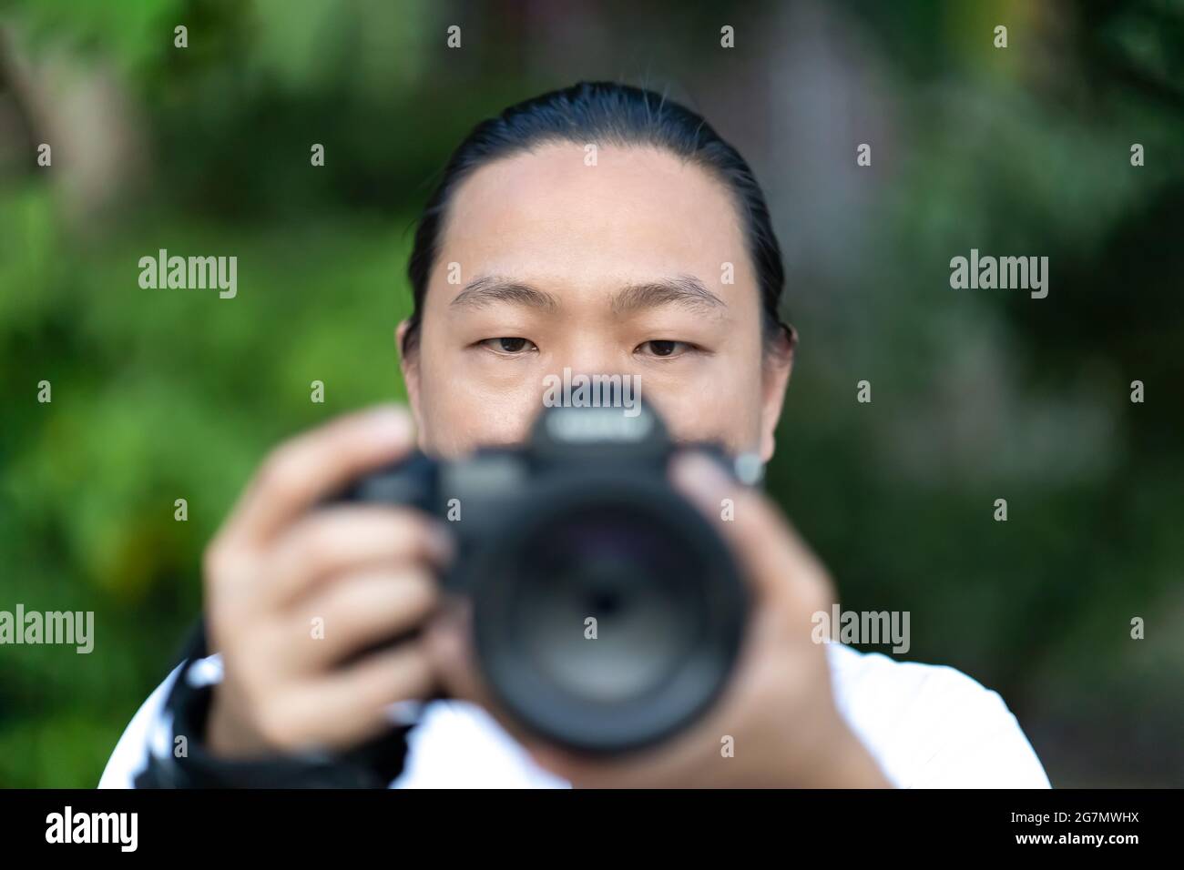 Konzentrieren Sie sich auf das asiatische Männergesicht, das er die Blur Medium Format Camera in der Hand hält, und bereiten Sie sich auf die Aufnahme vor ihm vor. Stockfoto