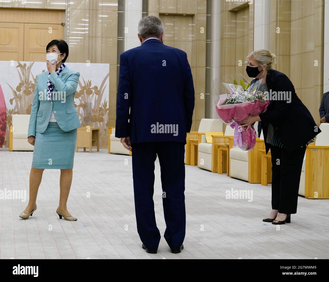 Tokio, Japan. Juli 2021. Die Gouverneurin von Tokio, Yuriko Koike (L), reagiert, als ihr an ihrem Geburtstag Blumen geschenkt werden, während Thomas Bach (C), Präsident des Internationalen Olympischen Komitees (IOC), vor ihrem Treffen in Tokio, Japan, am 15. Juli 2021 auf sie schaut. Quelle: Christopher Jue/Xinhua/Alamy Live News Stockfoto