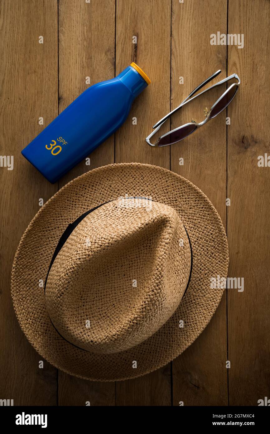 Strohhut, Sonnenschutzcreme und Sonnenbrille. Stockfoto