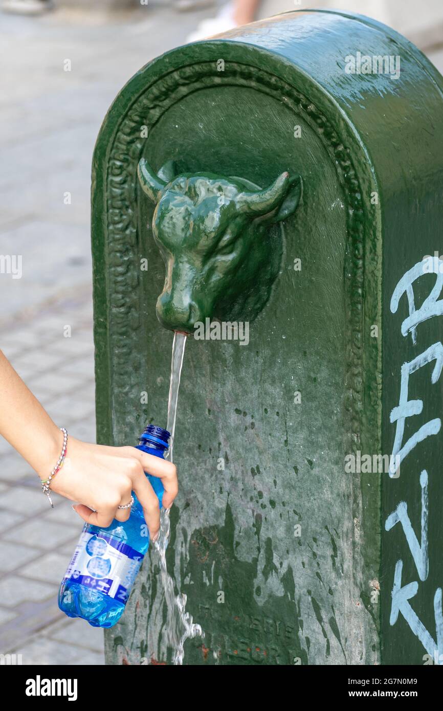 Hand eines Mädchens oder einer Frau, die eine Flasche frisches Wasser aus einem Brunnen in der Stadt, heißes Wetter und Sommerkonzept, verti, füllt Stockfoto