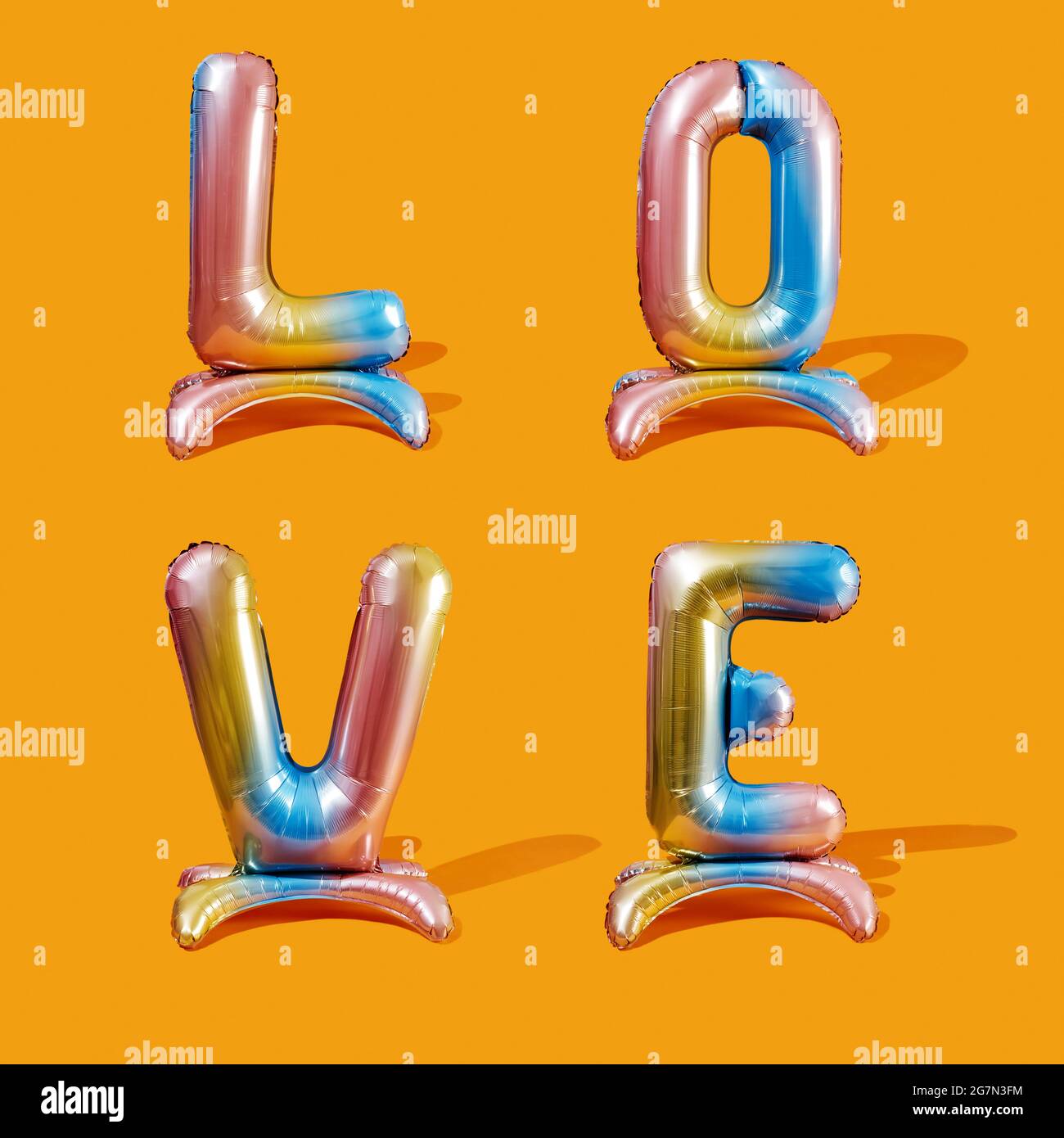 Nahaufnahme des Wortes Liebe geschrieben mit vier bunten, buchstabenförmigen Ballons auf einem orangen Hintergrund Stockfoto