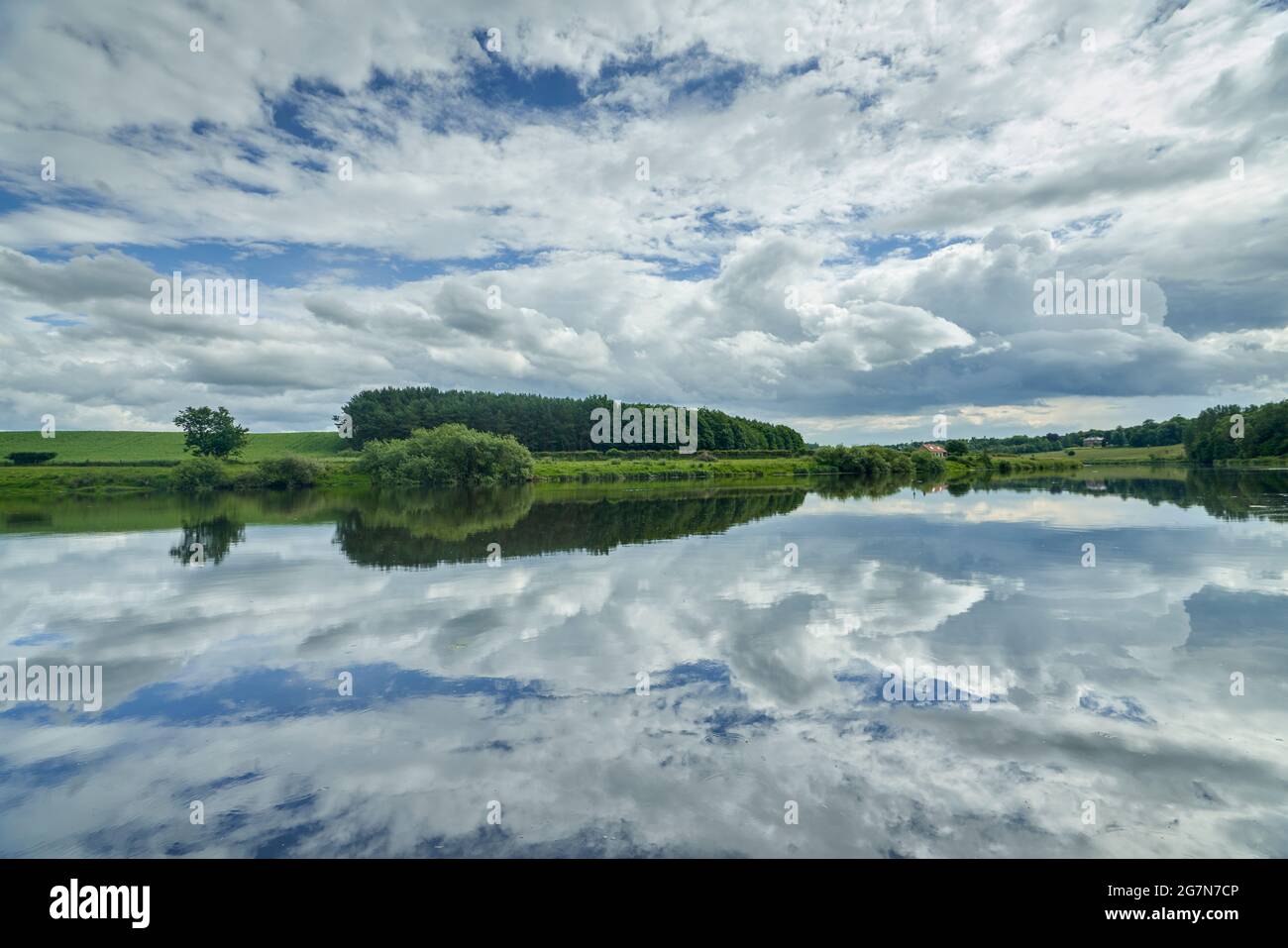 Dramatische Spiegelung des Himmels im Fluss Tweed an einem sonnigen Sommertag in den Scottish Borders. Stockfoto