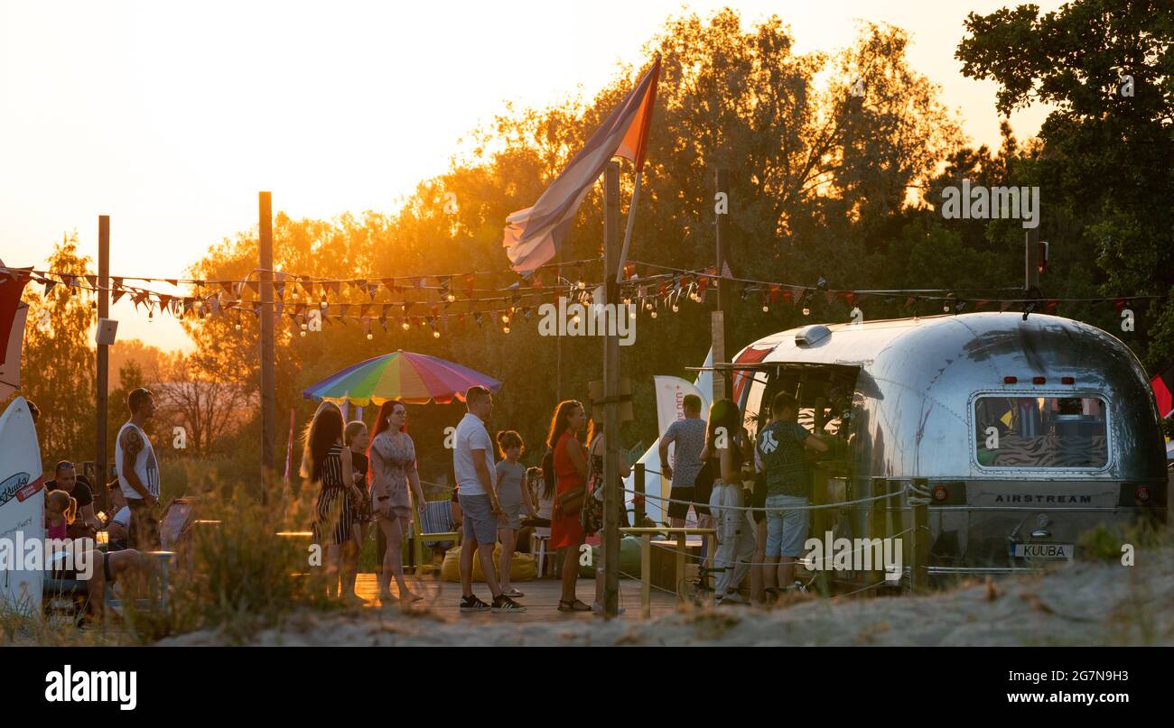 Parnu, Estland - 06.21.2021: Kleine Cocktailbar in der Nähe des Strandes namens Little Cuba. Am Strand standen die Leute Schlange, um billige Getränke zu kaufen. Perfekte Sonnenuntergänge in Estlands Sommerhauptstadt Parnu. Strandparty. Stockfoto