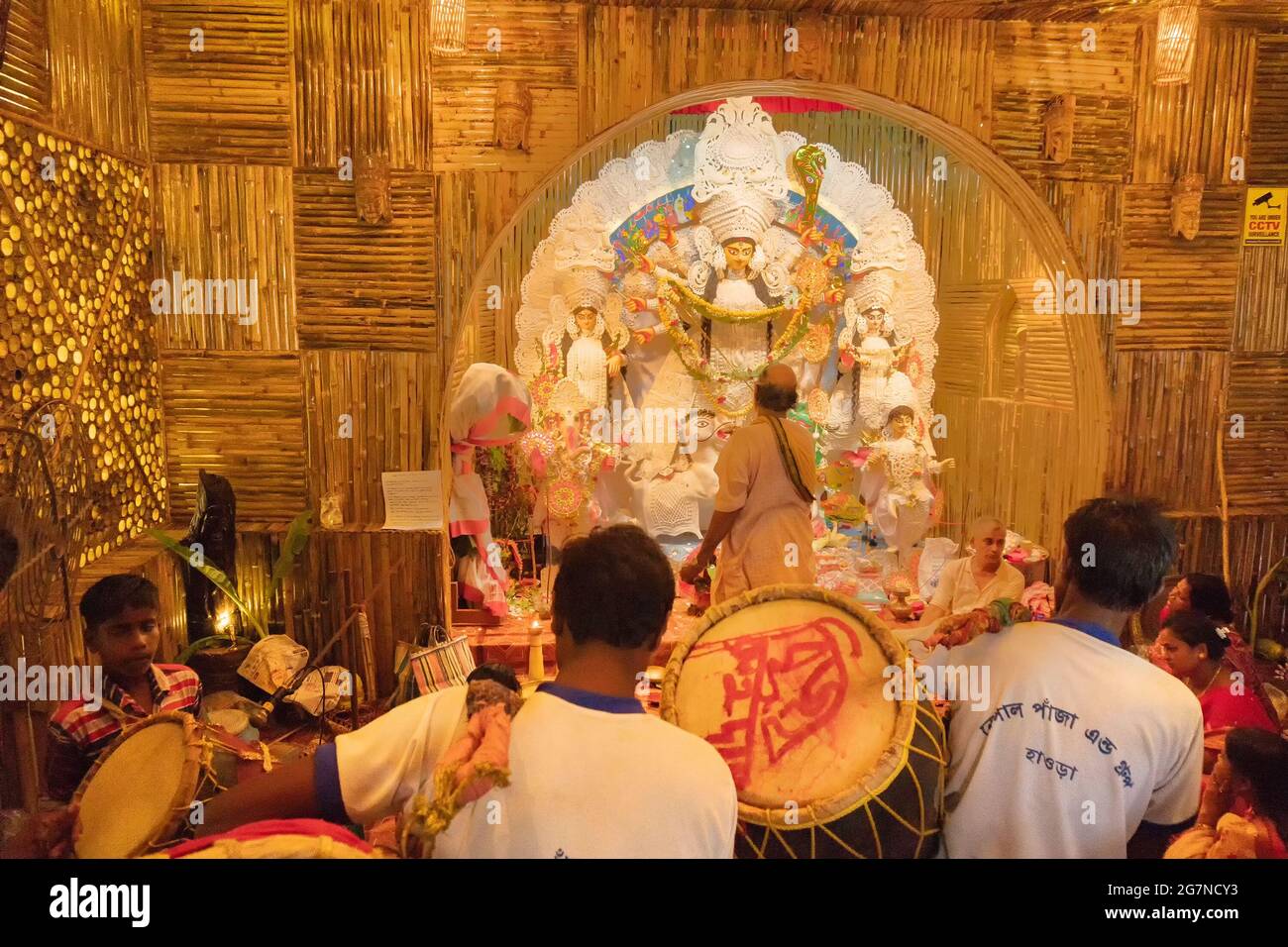 KOLKATA , INDIEN - 27. SEPTEMBER 2017 : Hindu-Priester verehrt Göttin Durga, während Dhaakis (Trommler) in seinem Rücken auftreten. Durga Puja Festival Stockfoto