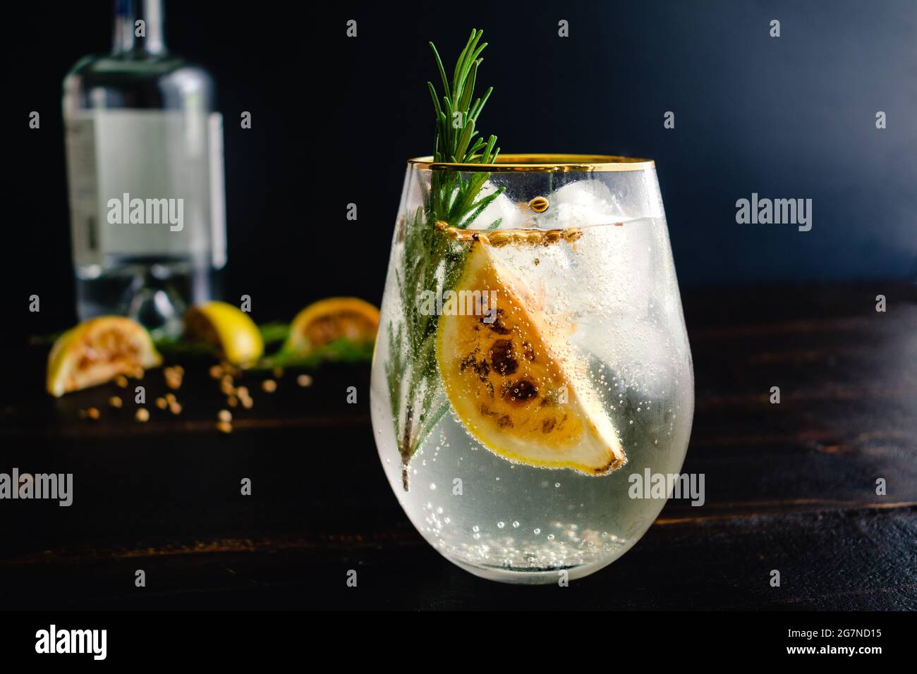 Verkohlte Zitrone, Rosmarin und Koriander Gin und Tonics: Gin und Tonic-Cocktails garniert mit verkohlten Zitronenkeilen und Aromaten Stockfoto