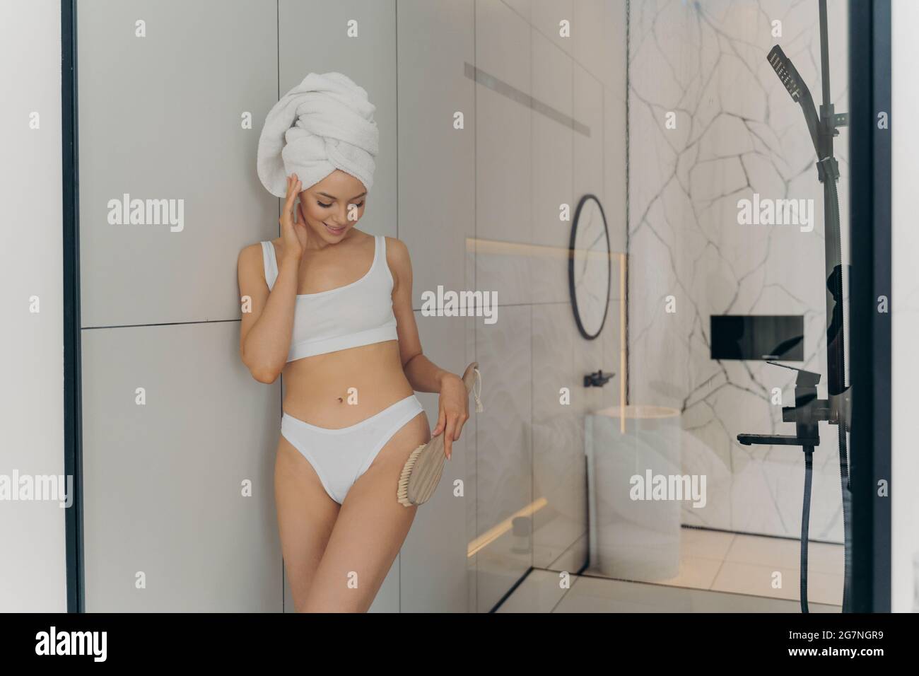Schöne weibliche Modell mit trockener Bürste in der Hand entspannend im Badezimmer Stockfoto
