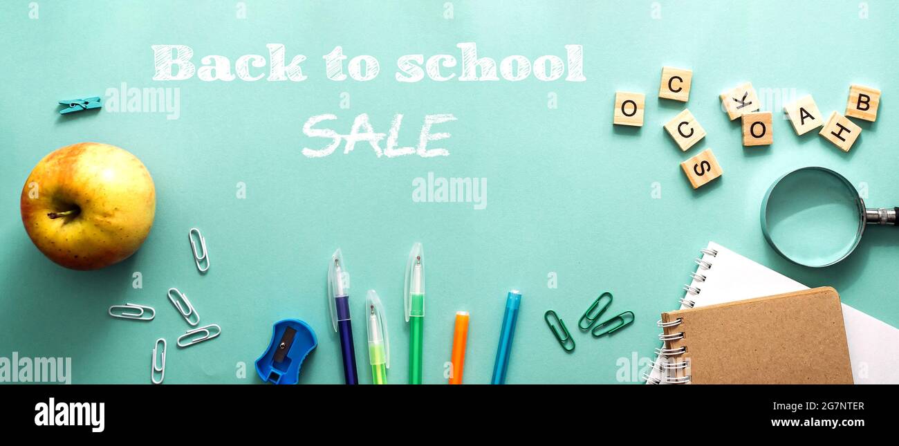 Sale Back to School Konzept. Farbige Stifte, leere Schule Notizbuch, Lupe, Apfel und andere Elemente auf einem blauen Hintergrund. Papeterie für die Stockfoto
