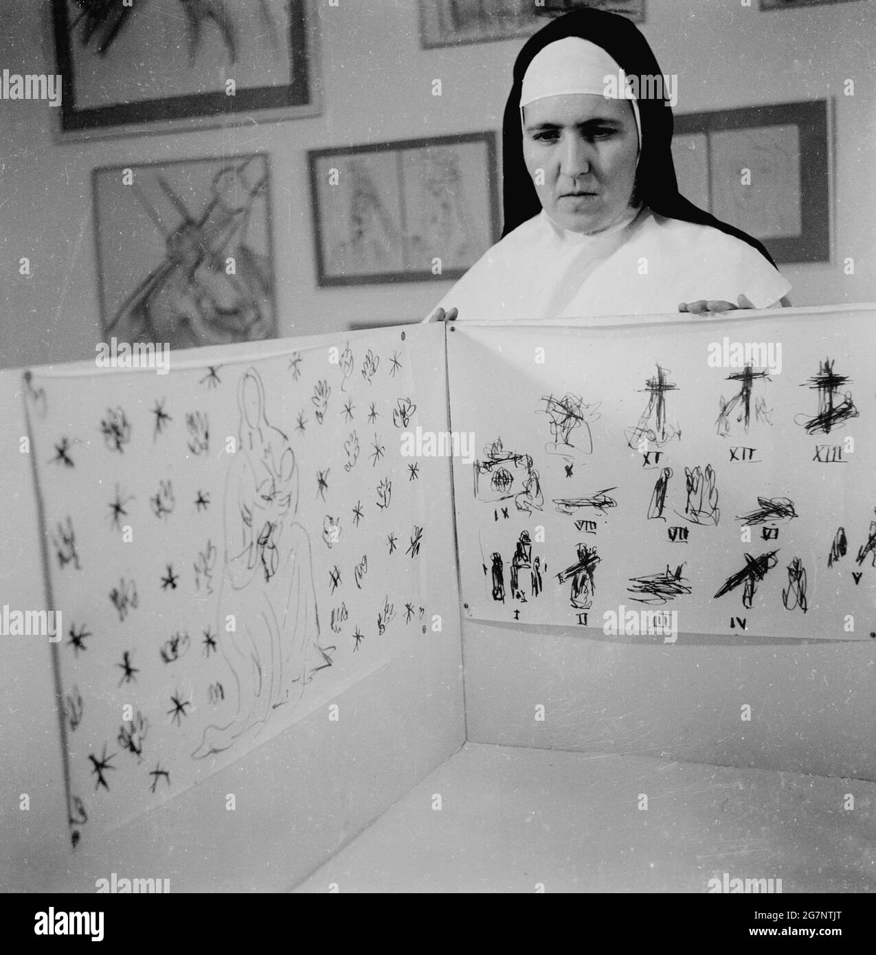 1951, Zeichnungen des französischen Künstlers Henri Matisse, in einer Ausstellung. Eine Dominikanerin, die die Skizzen von Matisse für das Innere der Chapel de Vence in Frankreich zeigt, einer kleinen katholischen Kapelle an der französischen Riviera. Sie wurde zwischen 1947 und 1951 nach Plänen und Zeichnungen von Matisse erbaut und dekoriert, der mit 77 Jahren mit der Arbeit an dem Projekt begann. Er wurde von einer jungen Krankenschwester, die ihn nach seiner Krankheit betreut hatte und die in das Dominikanerkloster in Vence eingetreten war, bei der Gestaltung der Kapelle um Hilfe gebeten. Stockfoto