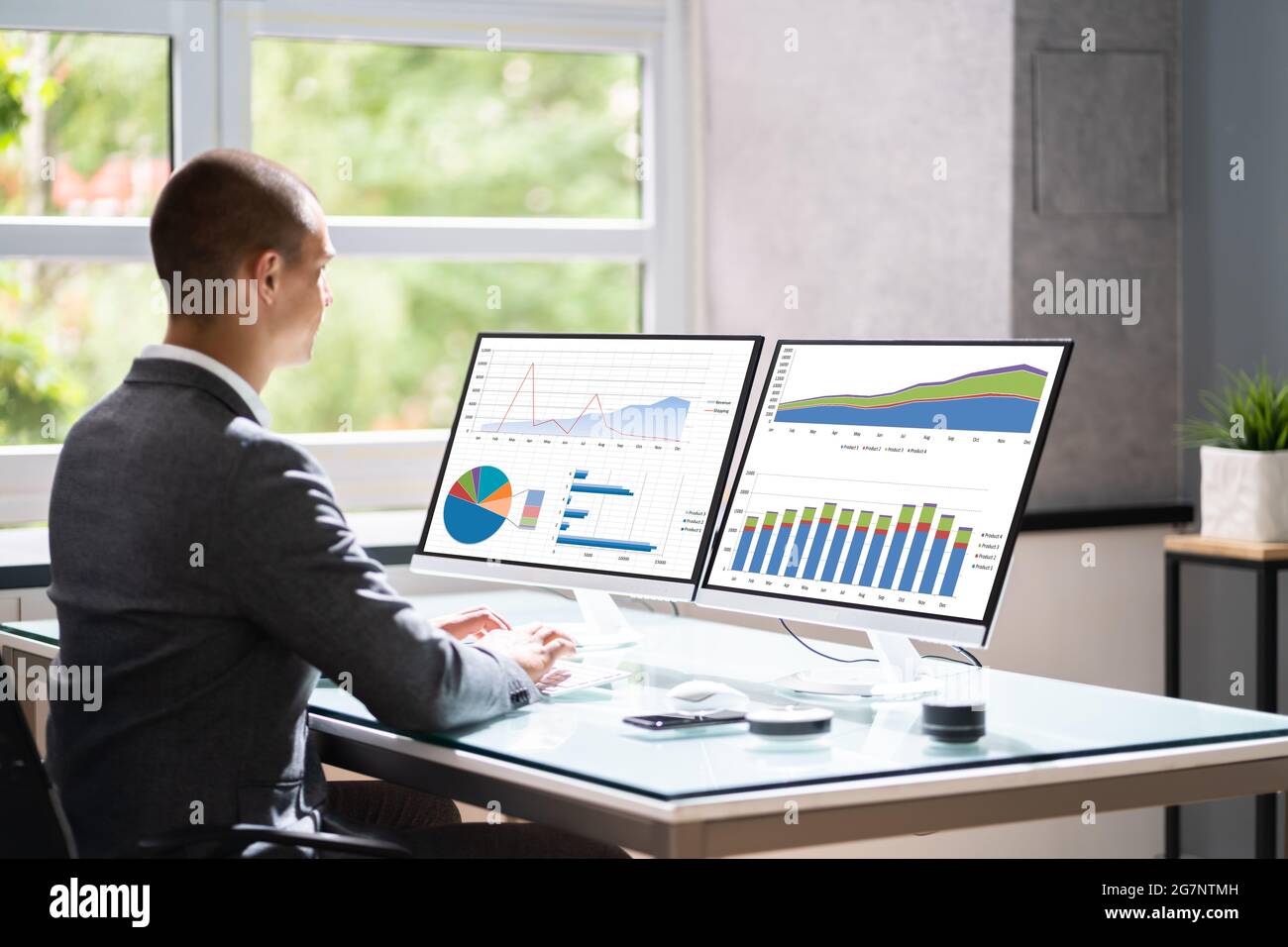 Geschäftsmann Im Büro Am Schreibtisch Mit Grafiken Auf Dem Computermonitor Stockfoto