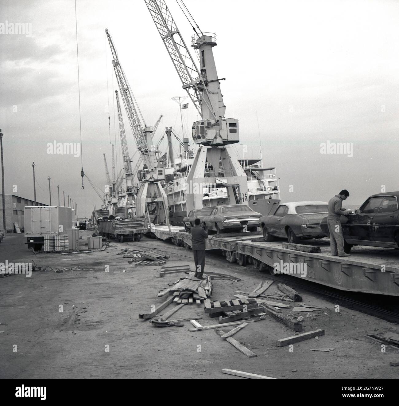 1960er Jahre, historisch, an den Docks in der Hafenstadt Jeddah, Saudi-Arabien, amerikanische Autos, die auf einer Eisenbahnstrecke geparkt wurden und in das Land importiert wurden, Stockfoto