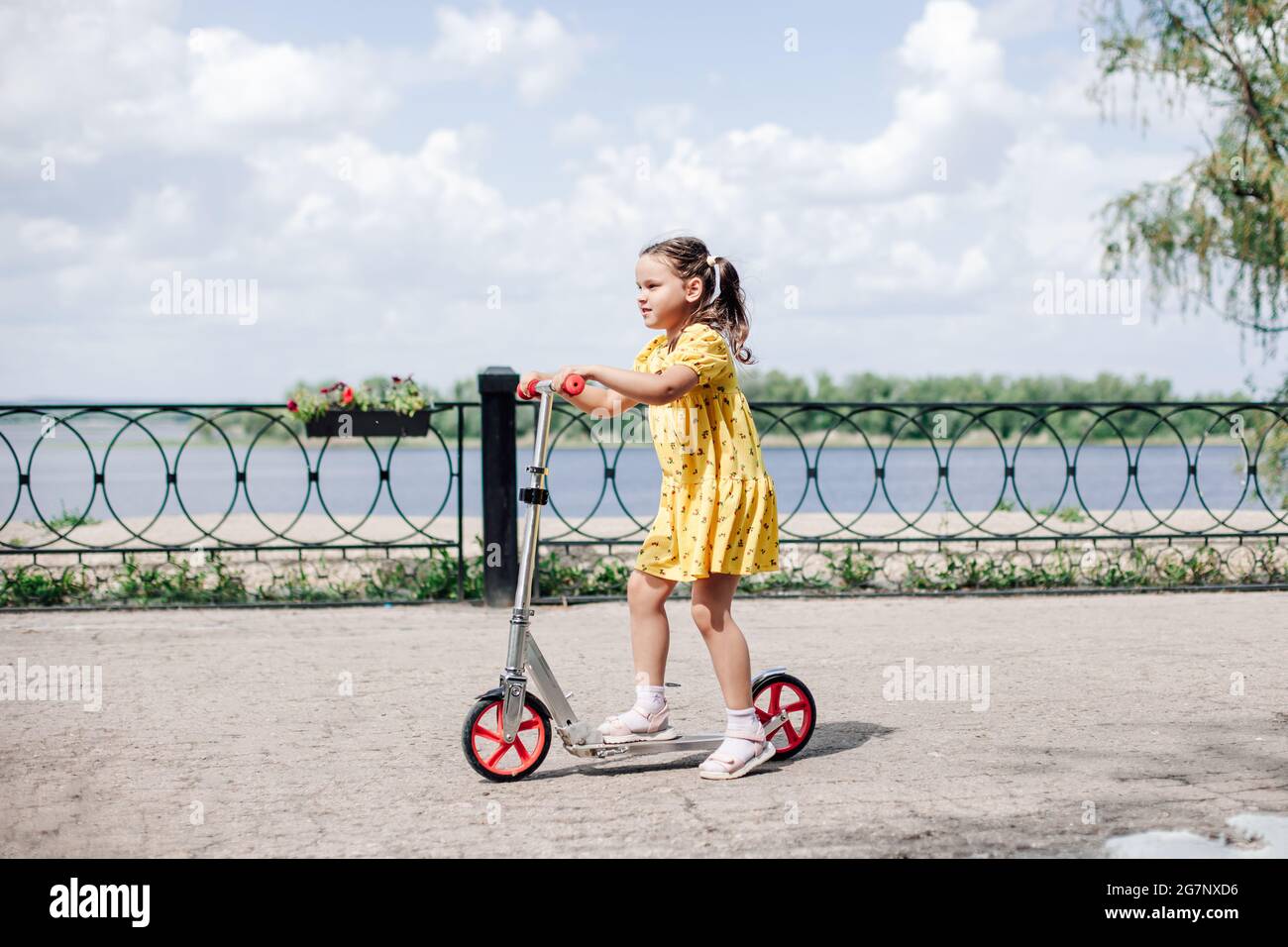 Kinder lernen, fahren, Roller in einem Park am Sommertag. Vorschulkind  Mädchen junge Helm anziehen zu helfen. Geschwister Roller fahren. Kinder  spielen gro Stockfotografie - Alamy