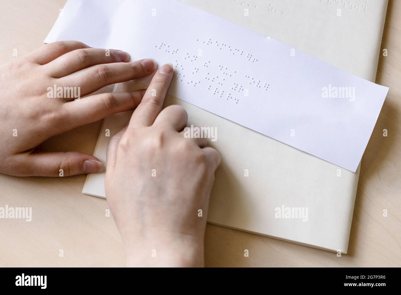 Die Fingerspitze einer blinden Frau liest die Notiz in Braille auf einem Blatt Papier aus nächster Nähe Stockfoto