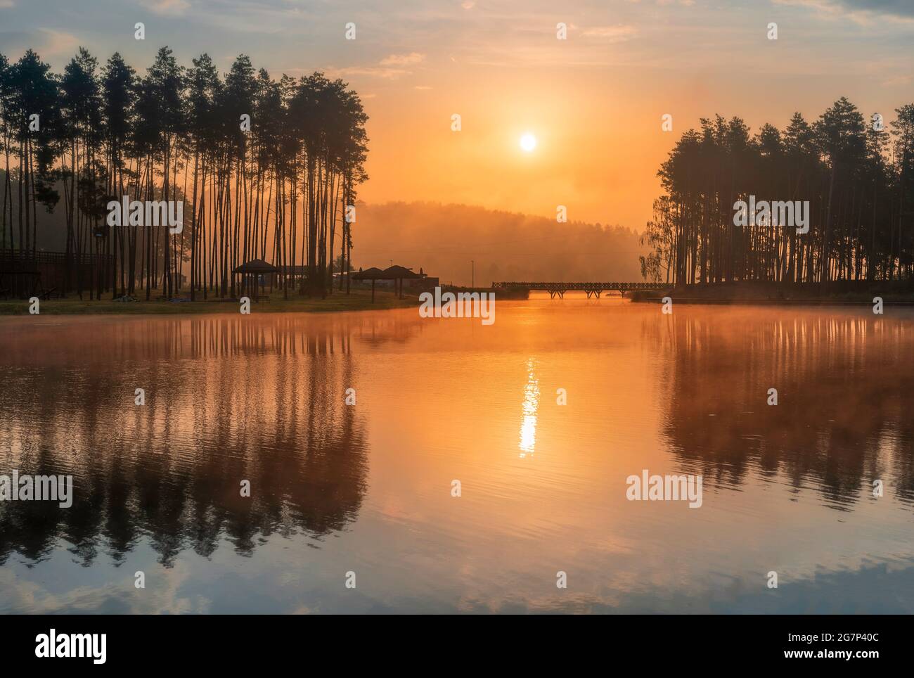 Schöner Sonnenaufgang über dem See in Krasnobród, Roztocze, Polen. Das Wasser ist im Morgenlicht von Bäumen umgeben. Stockfoto