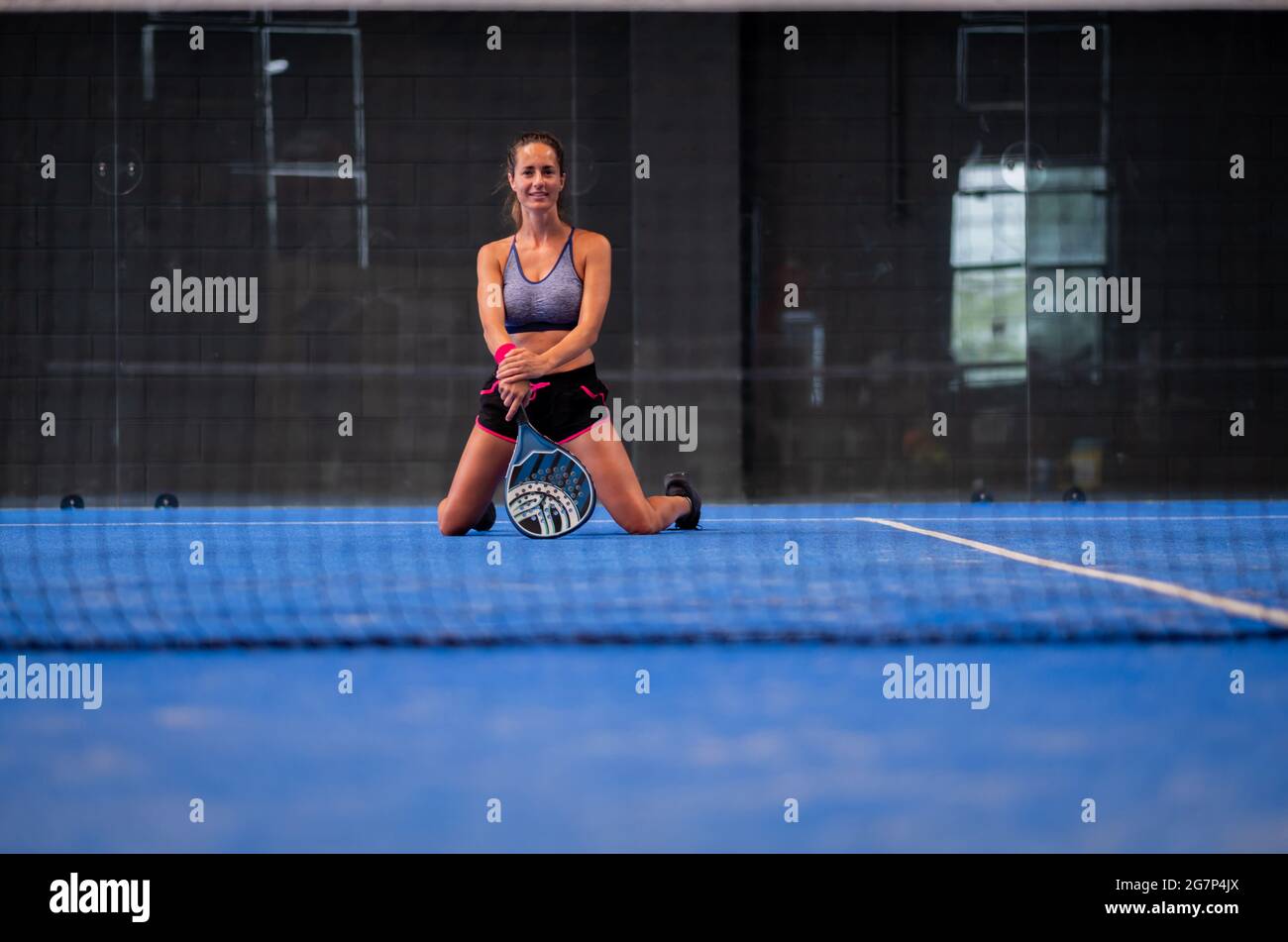 Porträt einer schönen Frau, die in der Halle einen Padel-Tennisplatz spielt Stockfoto